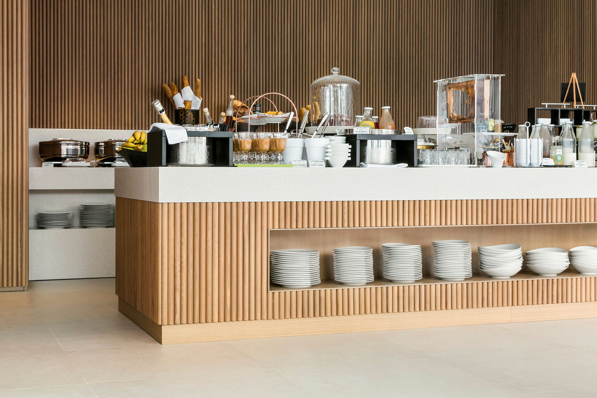 Morgenmadsbuffet med forskellige retter og drikkevarer på et moderne serveringsbord i træ og lyse detaljer. (AI-genereret tekst)