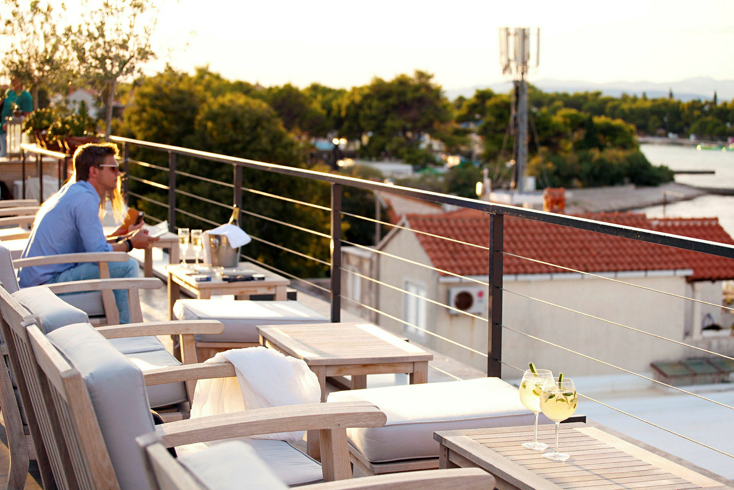 Terrasse med siddepladser og udsigt over omgivelser med huse og natur. (AI-genereret tekst)