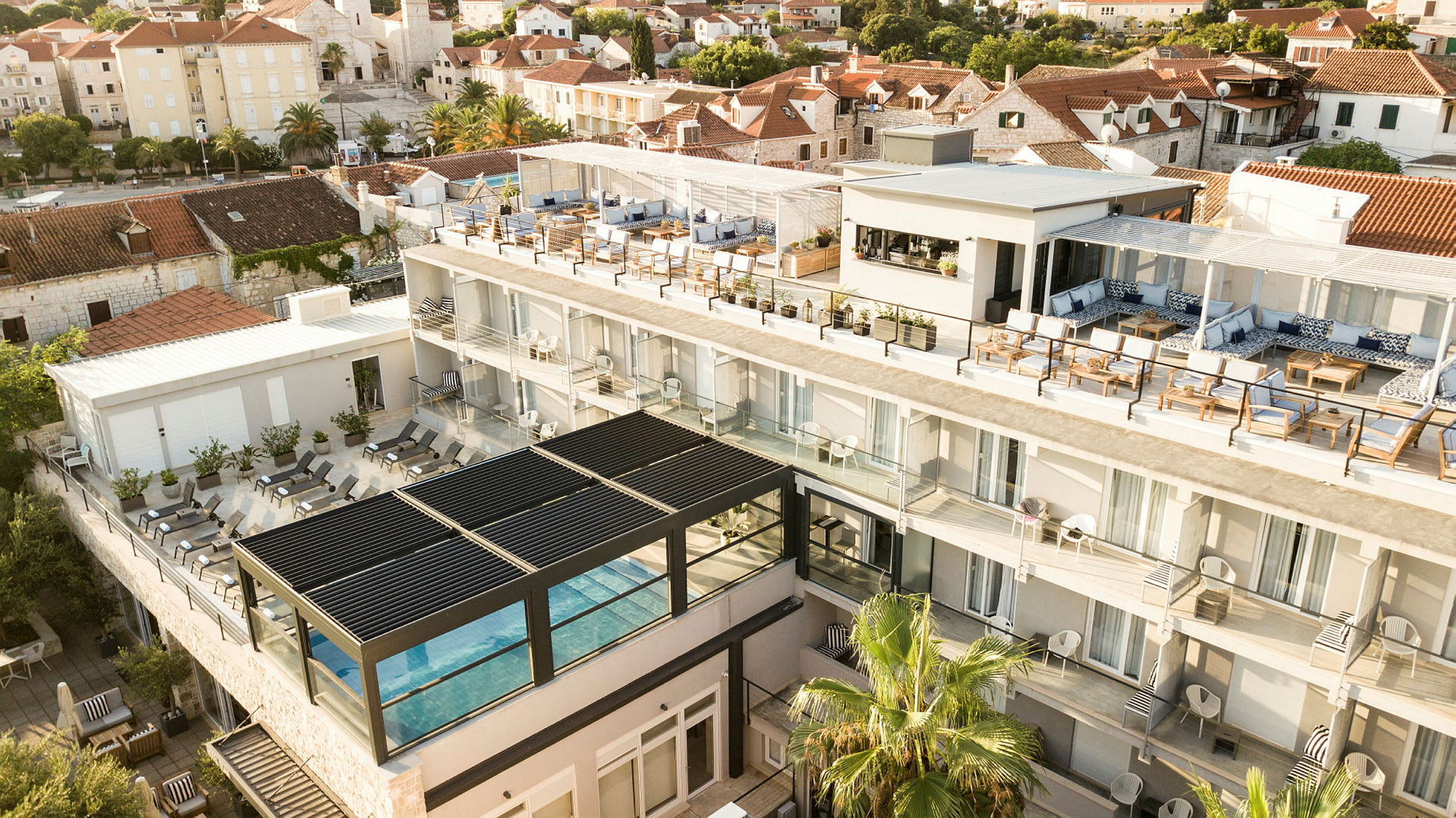 Hotelbygning med pool, terrasse og omkringliggende huse. (AI-genereret tekst)