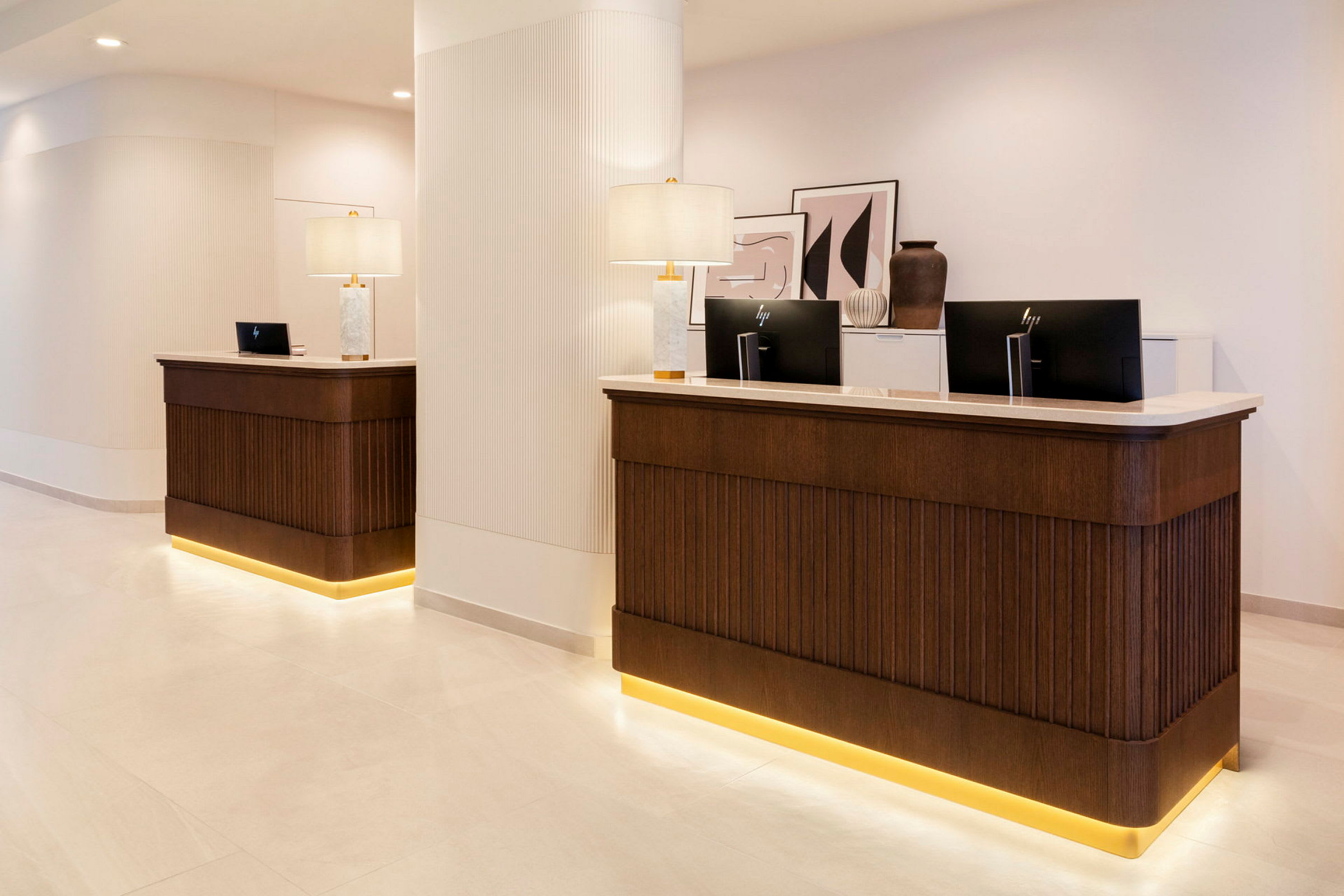 Hotellets reception med to skranker, baggrund med lamper og vægdekorationer. (AI-genereret tekst)
