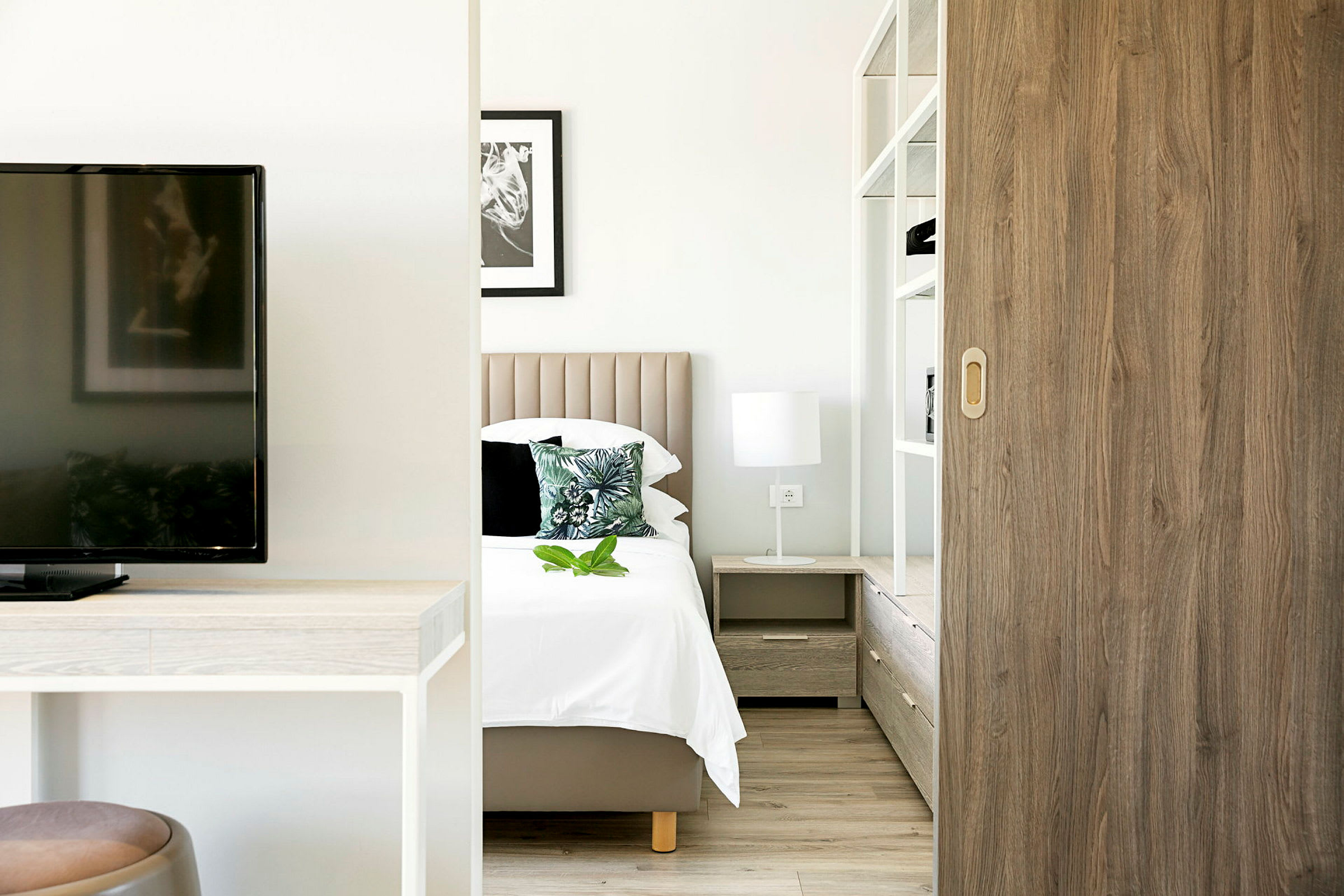 Moderne hotelværelse med seng, natbord og indretning. (AI-genereret tekst)