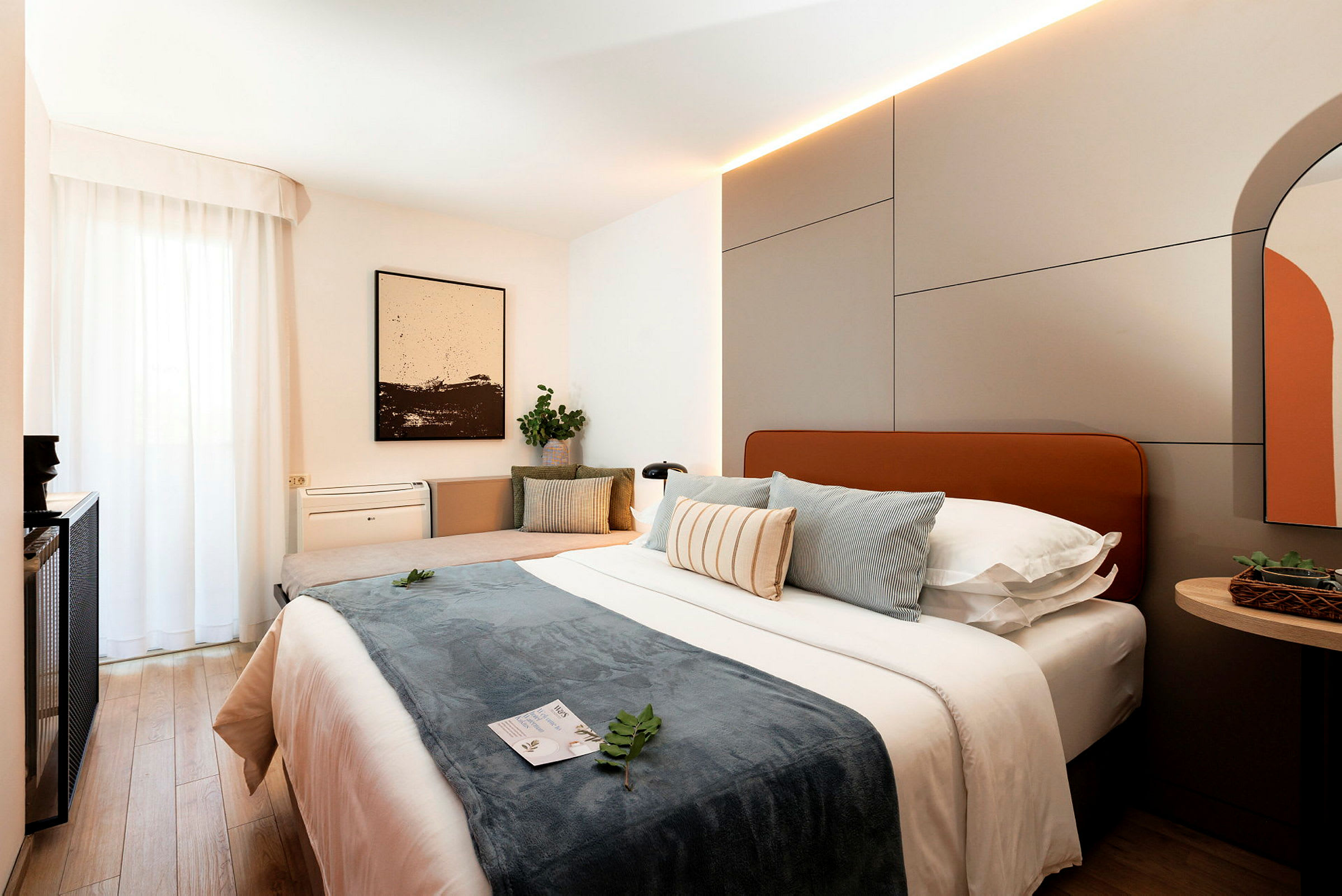 Et moderne hotelværelse med en stor seng, puder og indretningsdetaljer. (AI-genereret tekst)