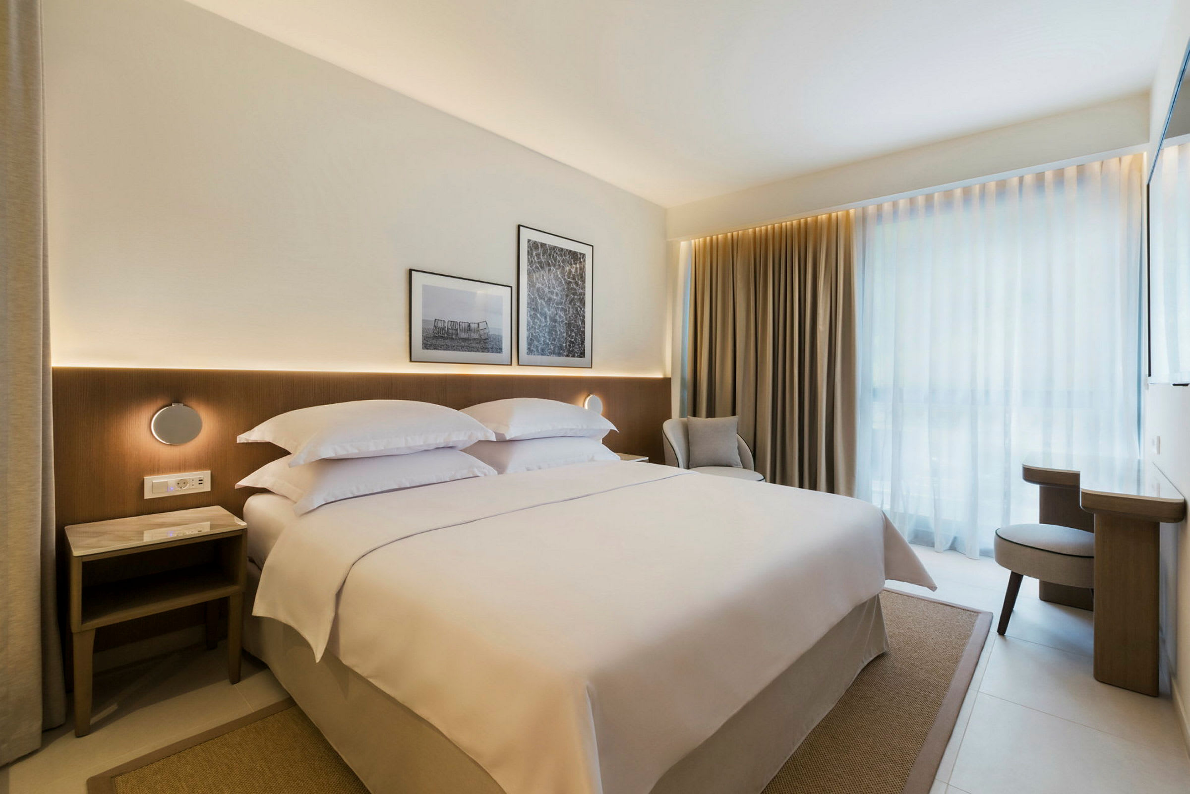 Moderne hotelværelse med en stor seng, gardiner og lys indretning. (AI-genereret tekst)