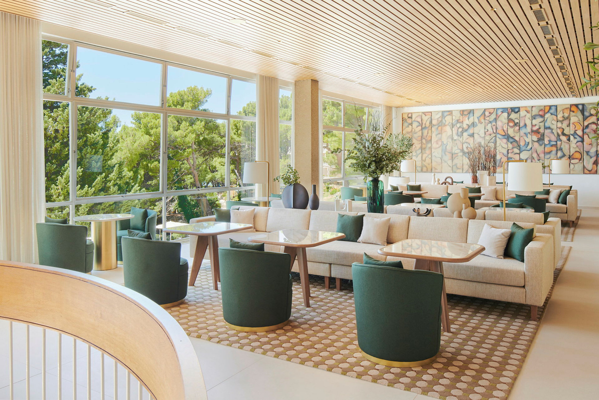 En lys og moderne lounge med grønne møbler, store vinduer og vægkunst. (AI-genereret tekst)