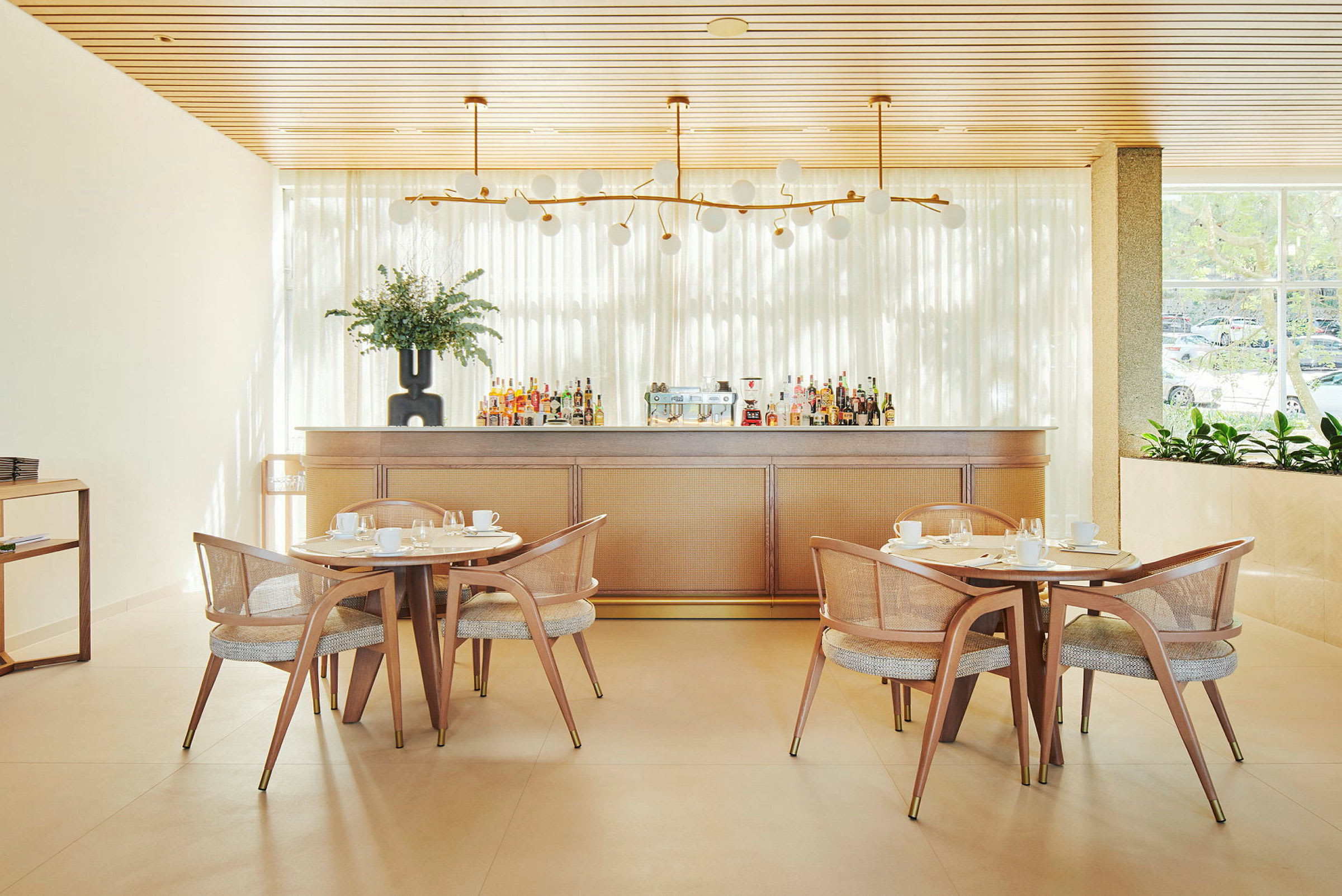 Billede af en lys restaurantinteriør med træborde, stole og en bardisk. (AI-genereret tekst)