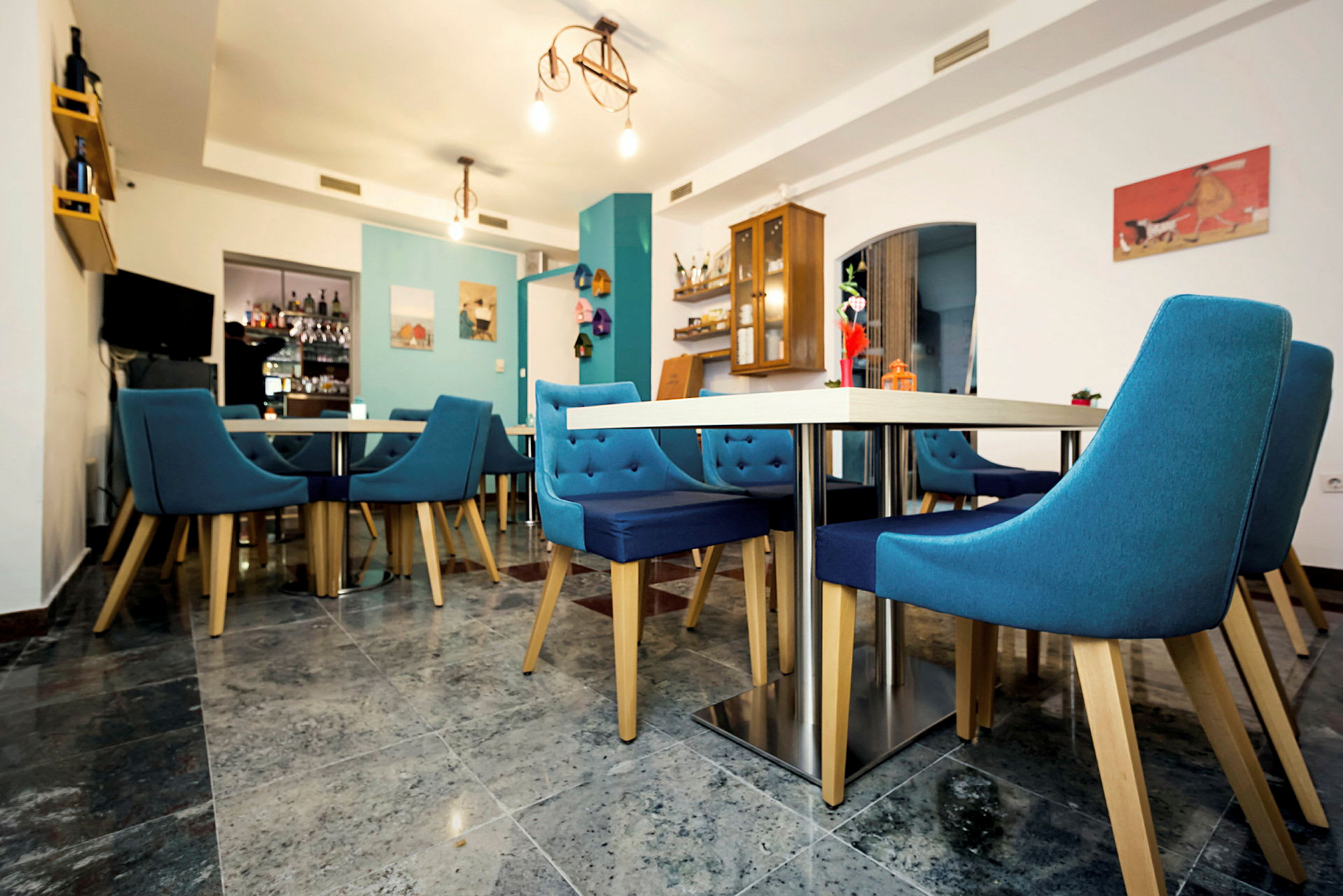 En restaurantinteriør med blå stole og borde. (AI-genereret tekst)