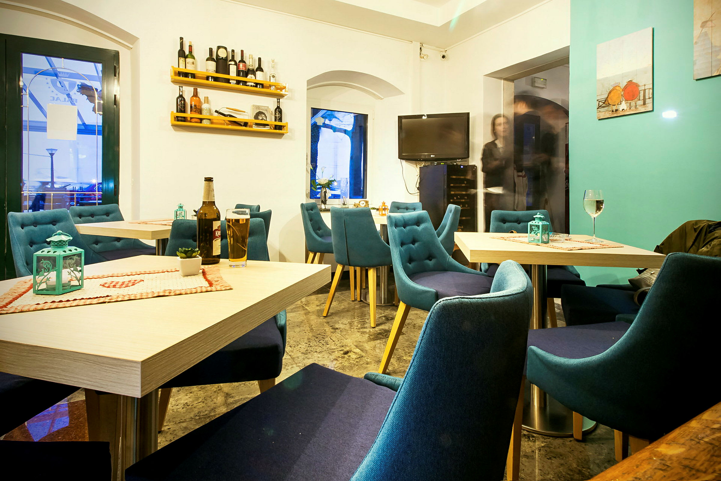 En lys og hyggelig restaurant med blå stole og dækkede borde. (AI-genereret tekst)