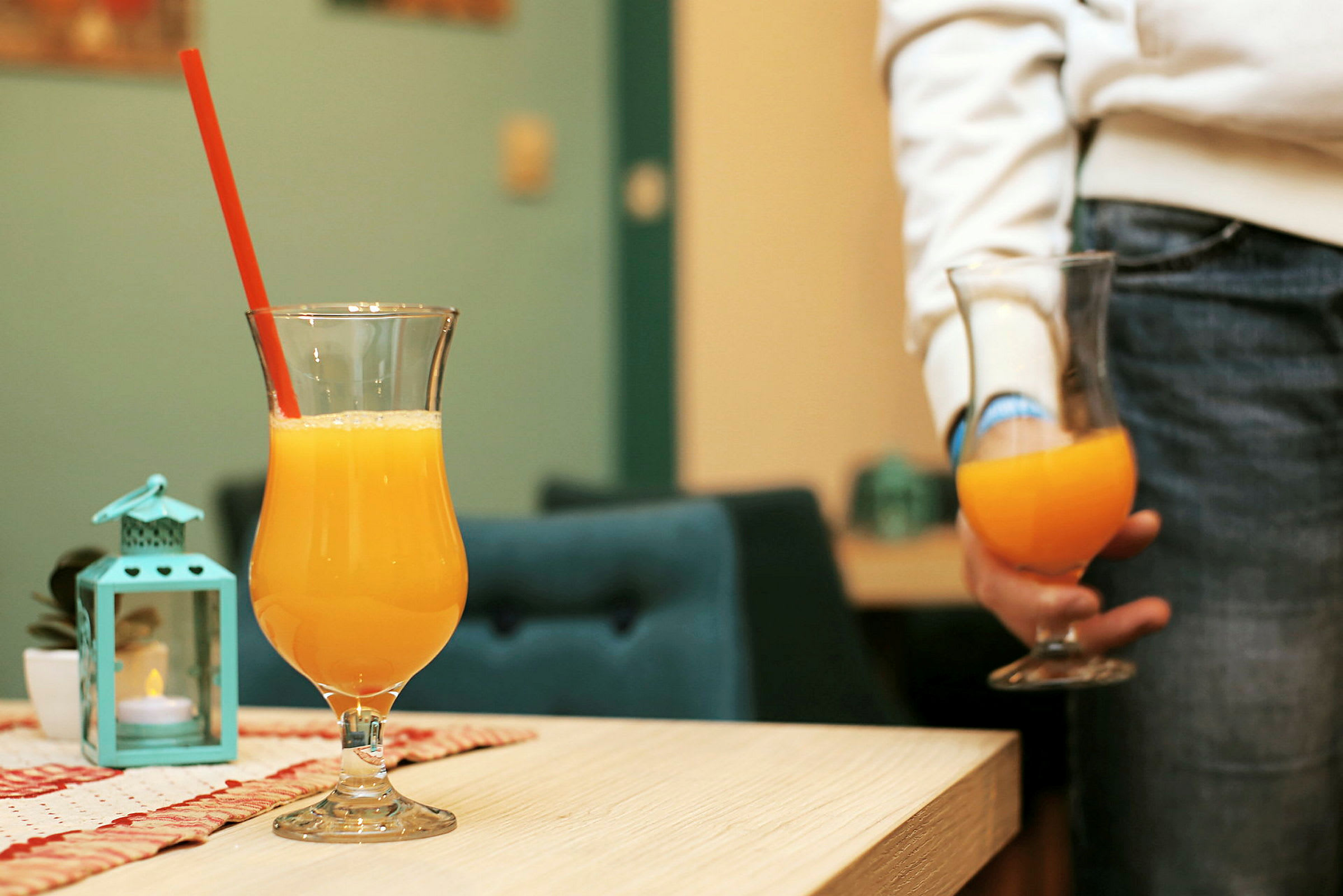 To glas med appelsinjuice, ét på et bord og ét holdes i hånden. (AI-genereret tekst)