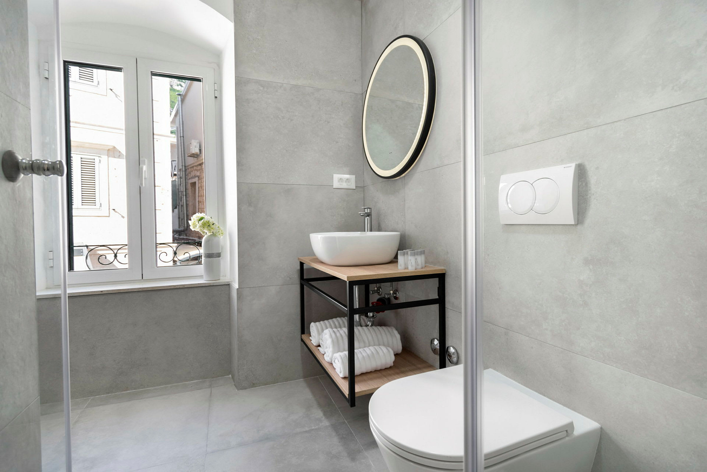 Moderne badeværelse med håndvask, rund spejl og toilet. (AI-genereret tekst)