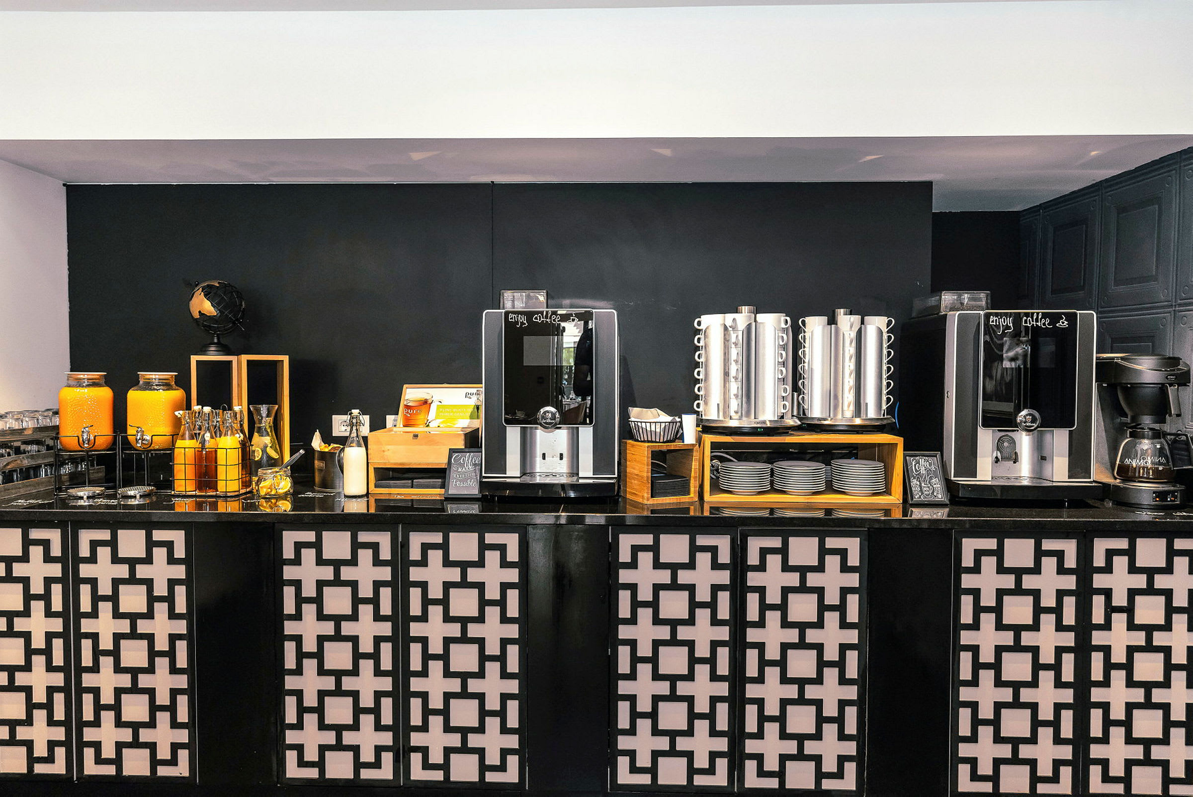 Billede af en kaffestation med automater, termobeholdere og juicebeholdere. (AI-genereret tekst)