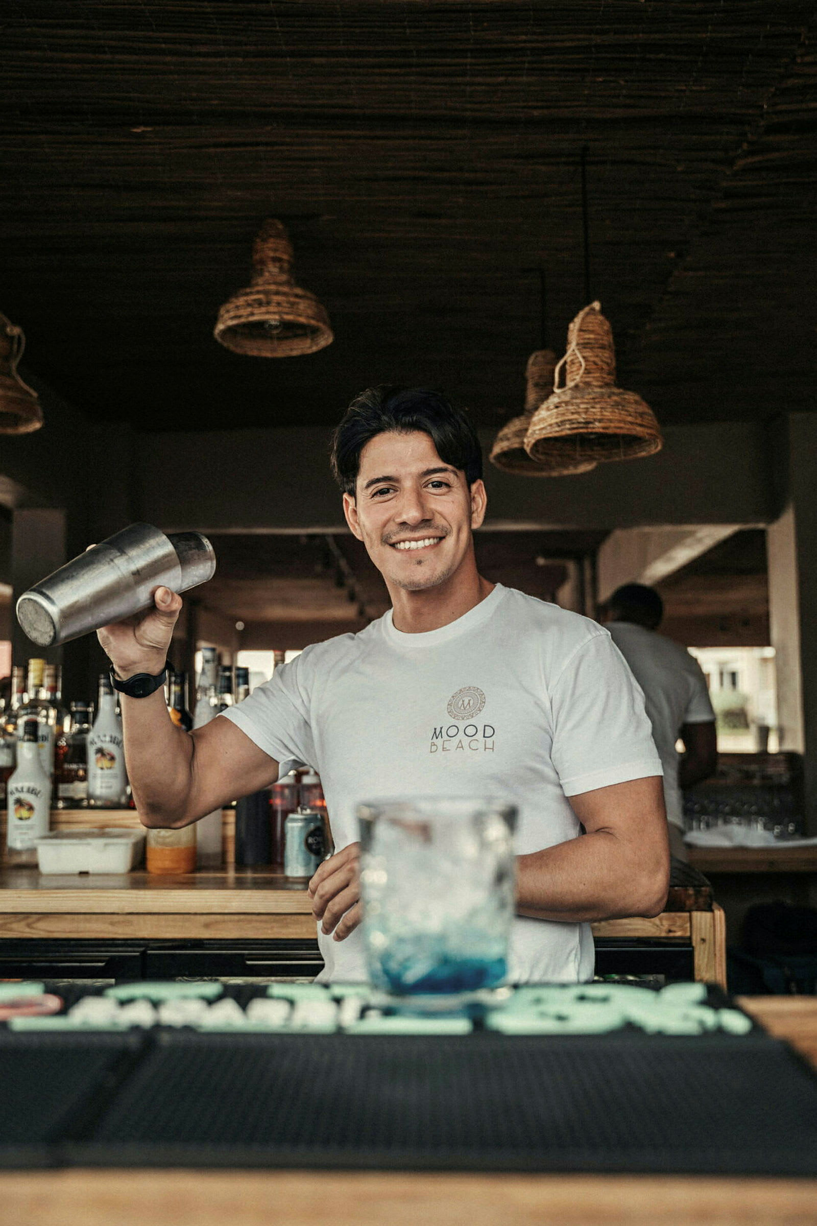 En bartender holder en cocktailshaker bag en bardisk. (AI-genereret tekst)