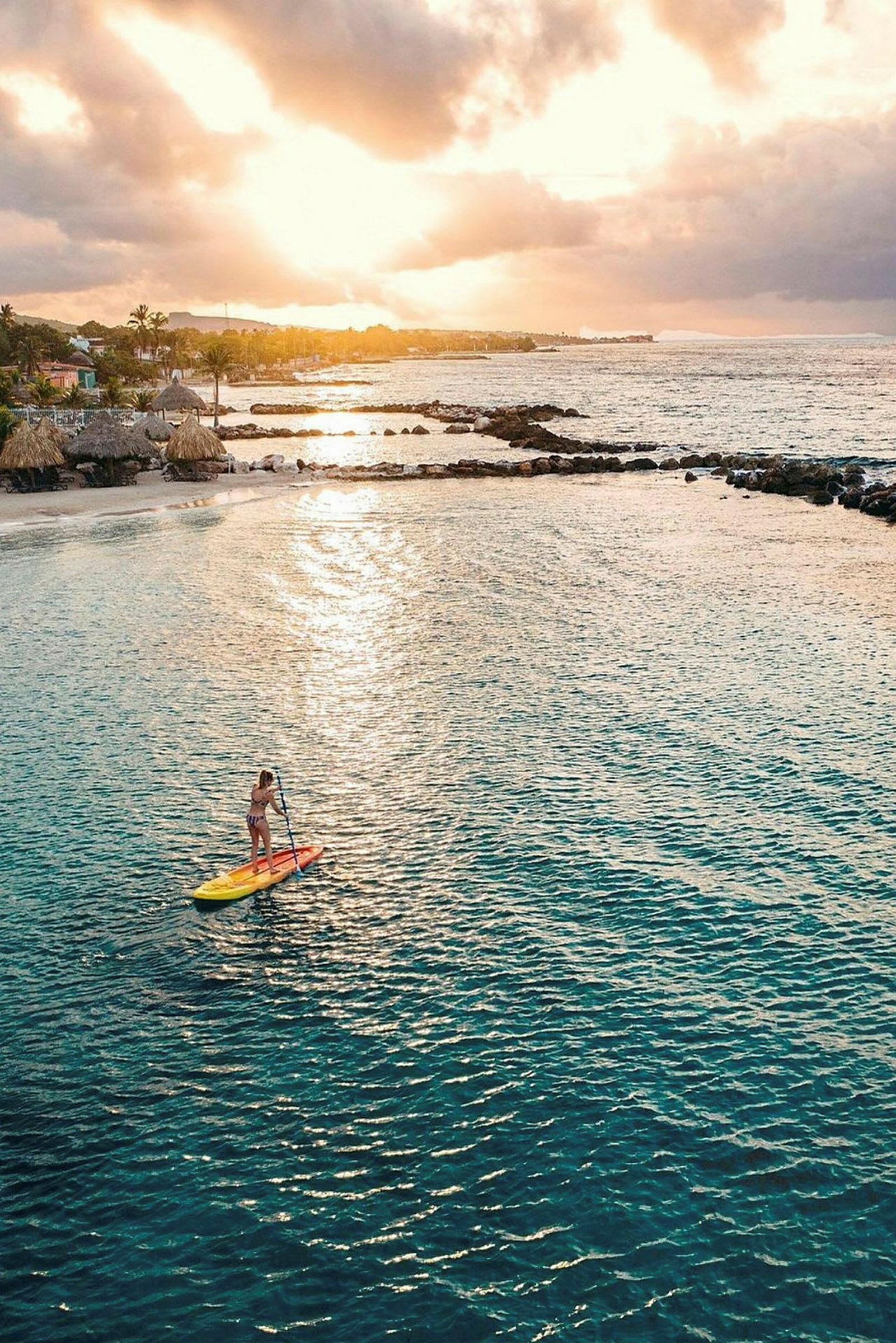 En person på et paddleboard i en rolig bugt med en gylden solnedgang i baggrunden. (AI-genereret tekst)