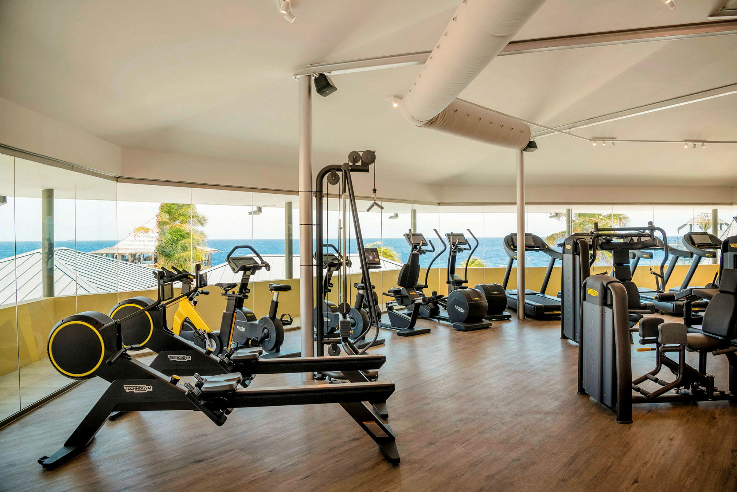 Fitnessrum med træningsudstyr og udsigt over havet. (AI-genereret tekst)