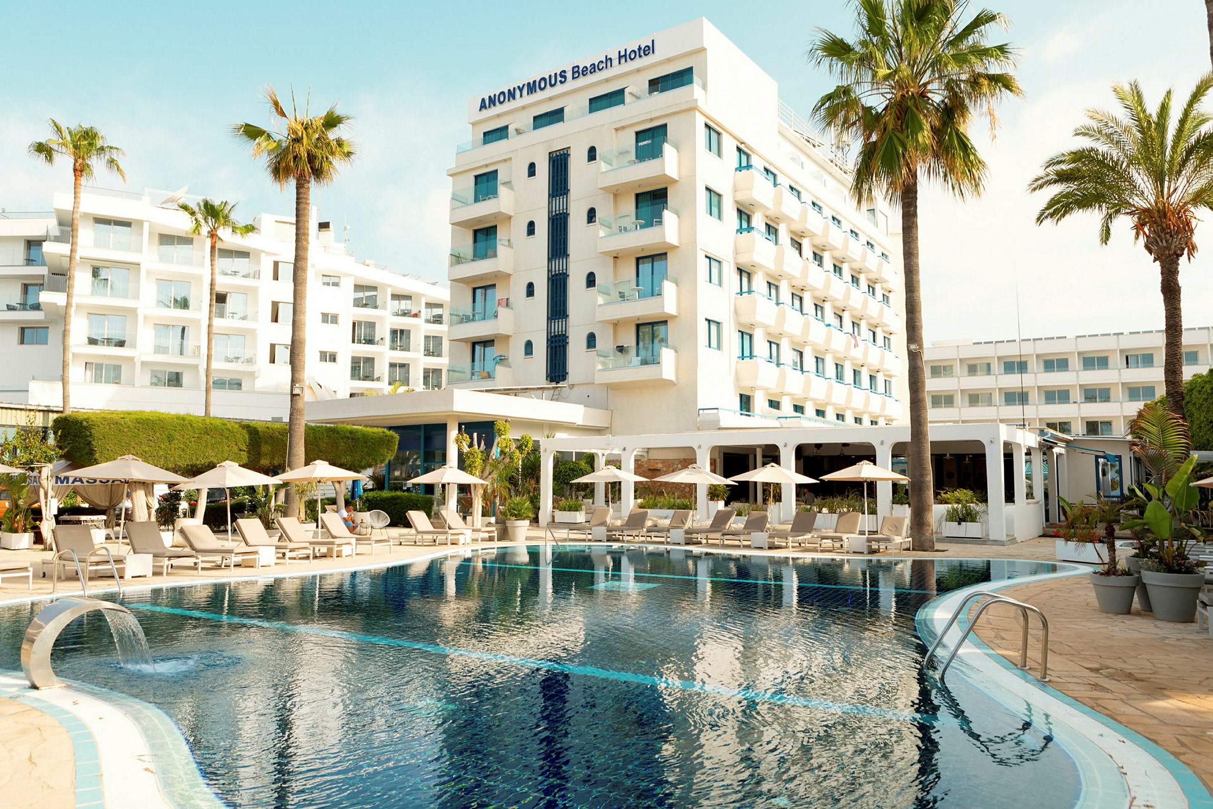 Hotel med pool, liggestole og parasoller i forgrunden. (AI-genereret tekst)