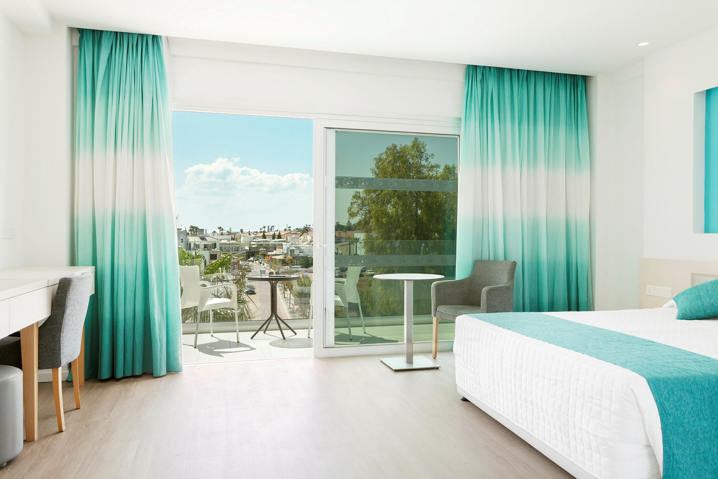 Hotelværelse med havudsigt gennem store vinduer og balkon. (AI-genereret tekst)