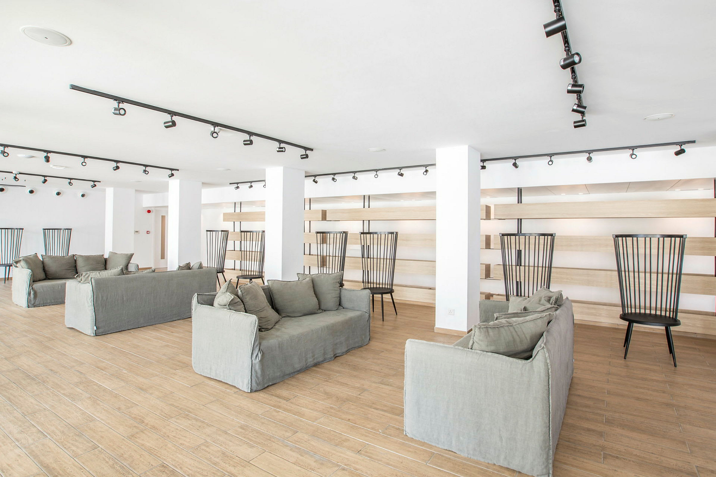 Et lyst rum med flere sofaer og stole, gulvet er lavet af træ, og rummet er indrettet med moderne design. (AI-genereret tekst)