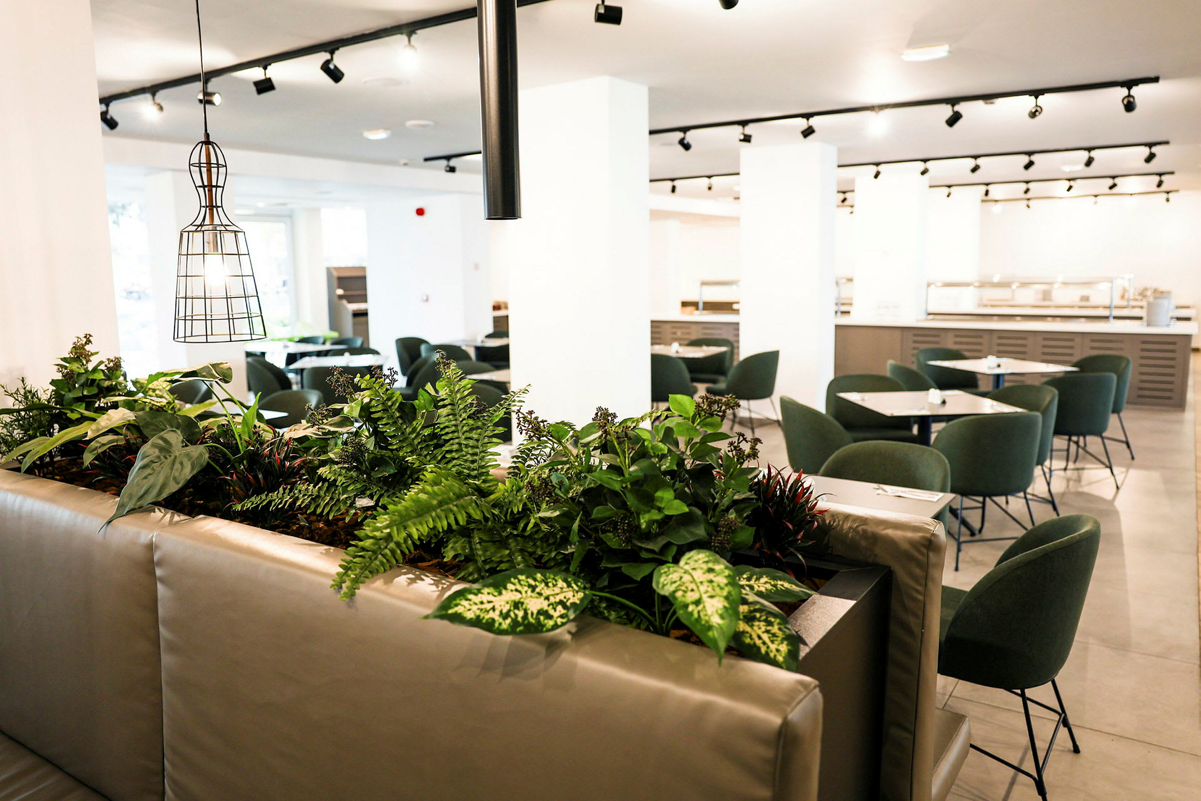 Et moderne indrettet spiseområde med grønne stole og planter som dekoration. (AI-genereret tekst)