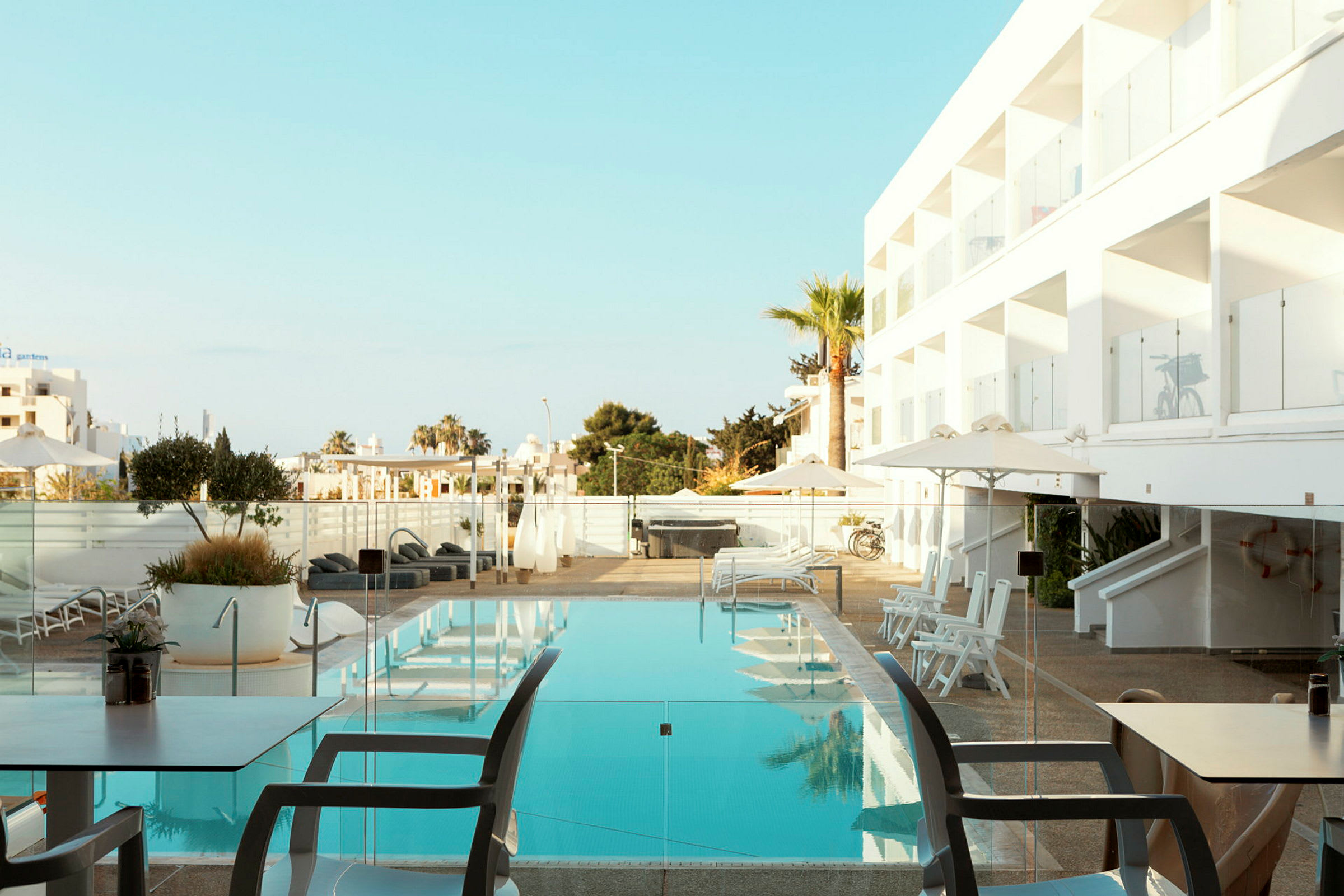 Swimmingpool ved hotel med liggestole og parasoller. (AI-genereret tekst)