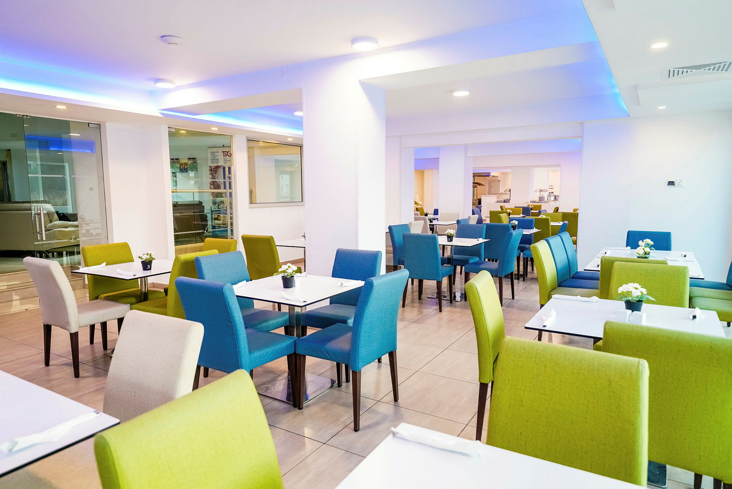 En restaurant med borde og stole i grønne og blå farver. (AI-genereret tekst)