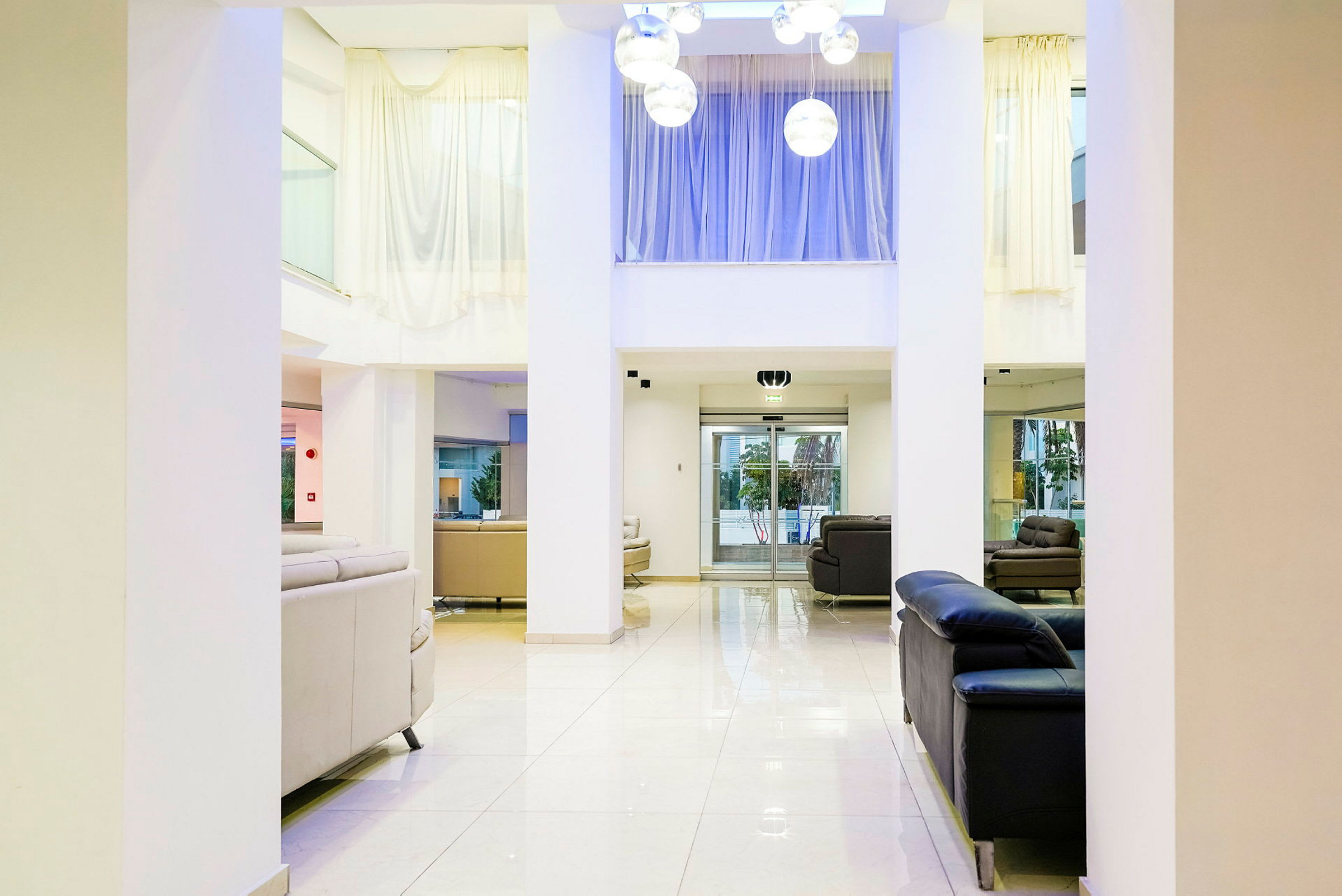 Lys hotellets lobby med sofagrupper og store vinduer. (AI-genereret tekst)