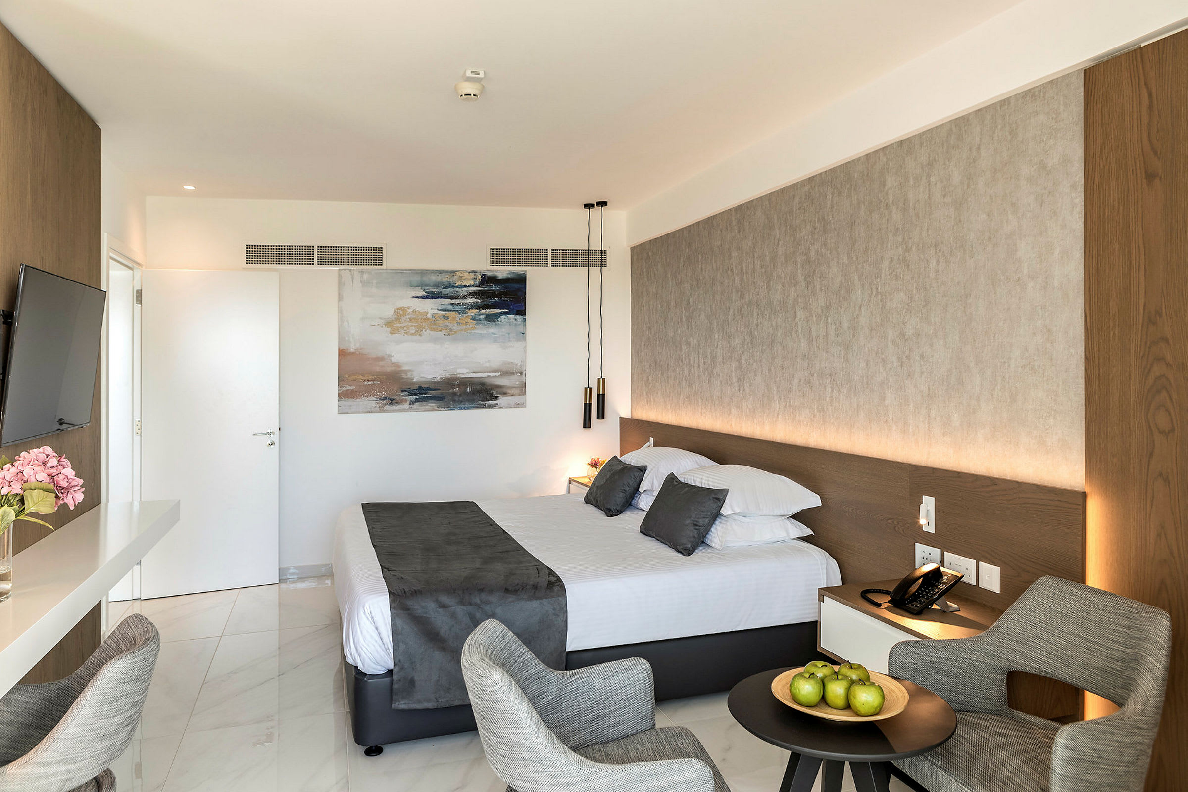Hotelværelse med en dobbeltseng, en siddegruppe og kunst på væggen. (AI-genereret tekst)