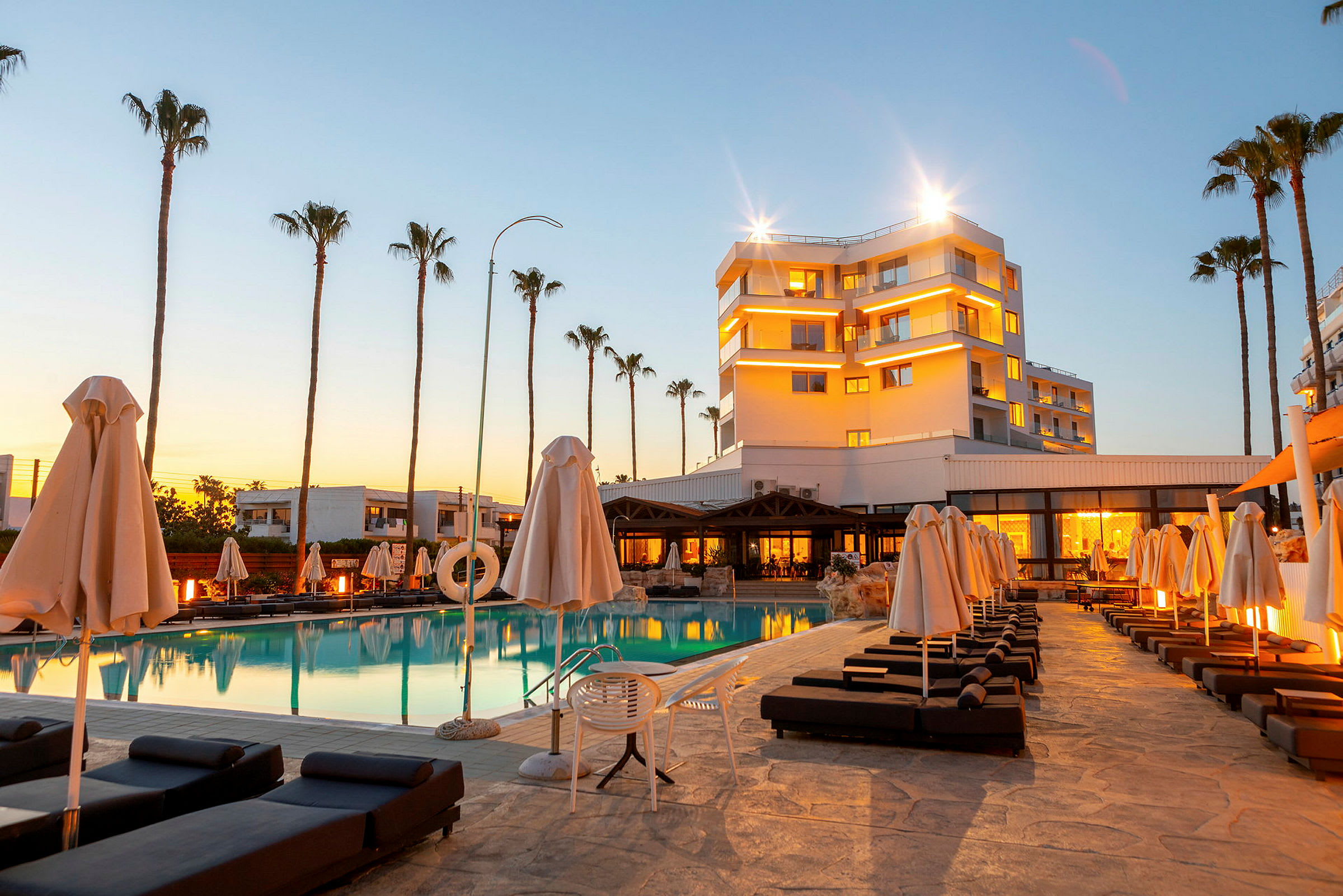 Hotel ved en pool med liggestole og parasoller. (AI-genereret tekst)