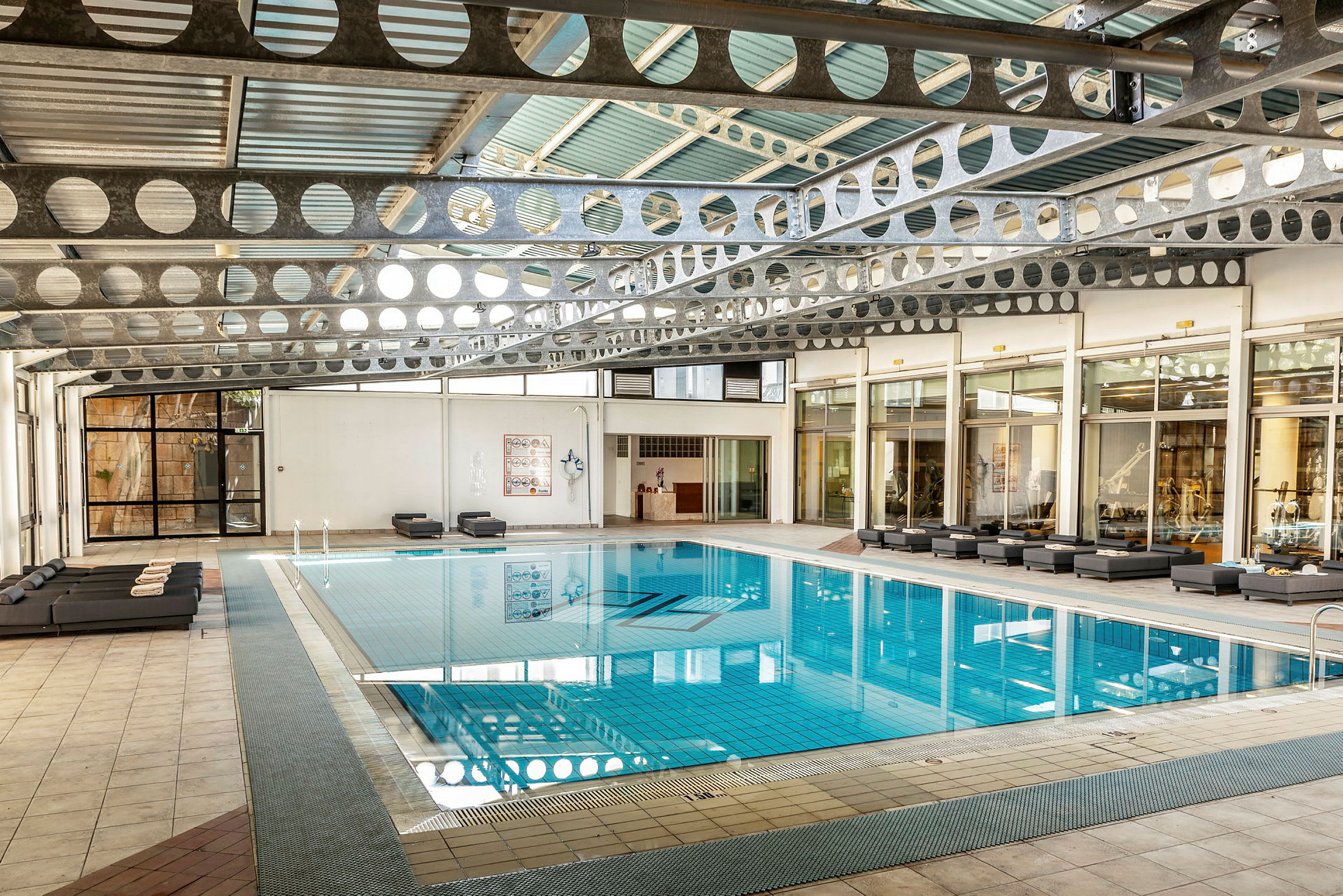 En indendørs pool med siddepladser omkring, omgivet af glasvægge. (AI-genereret tekst)