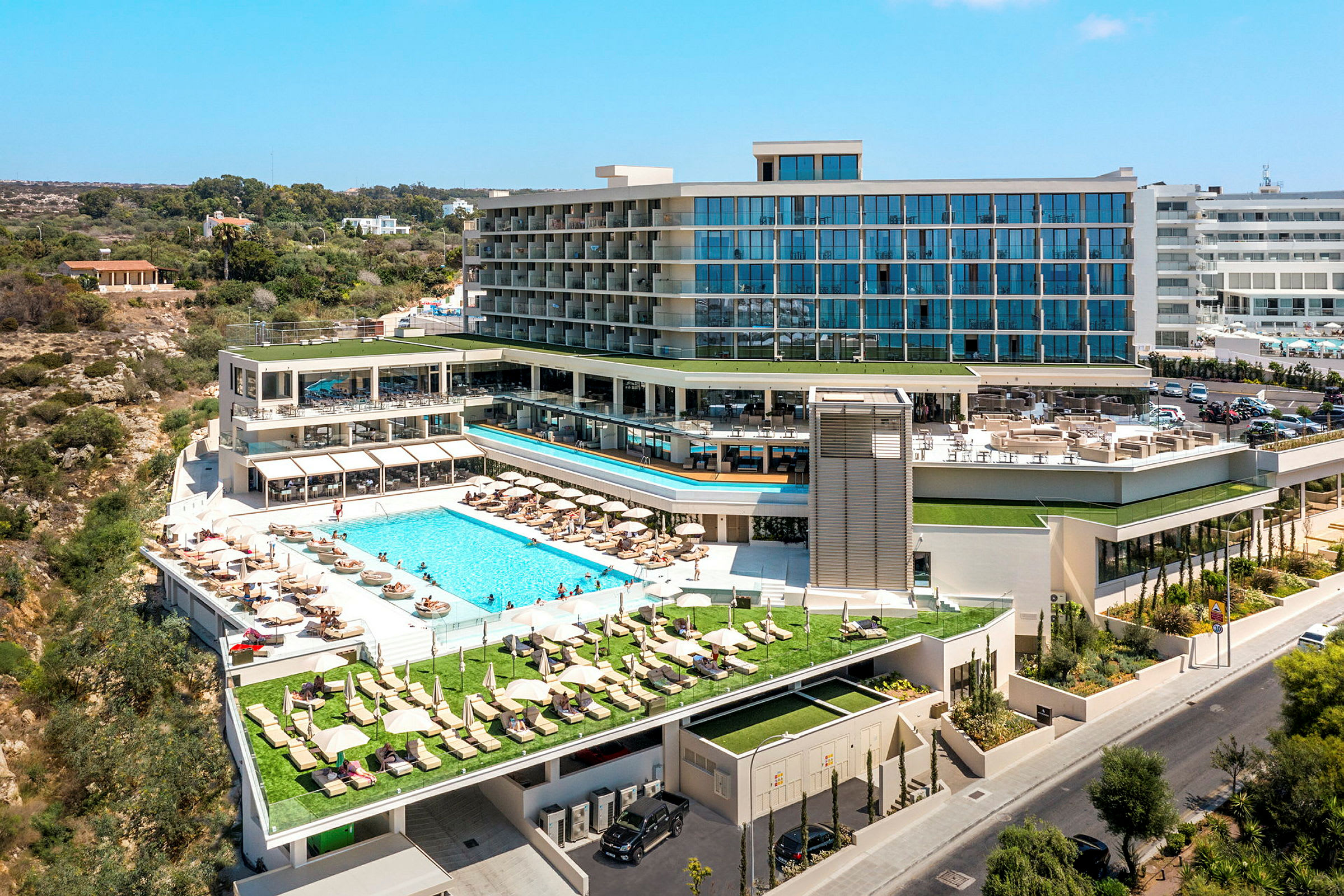 Udsigt til et moderne hotel med udendørs pool og liggestole. (AI-genereret tekst)