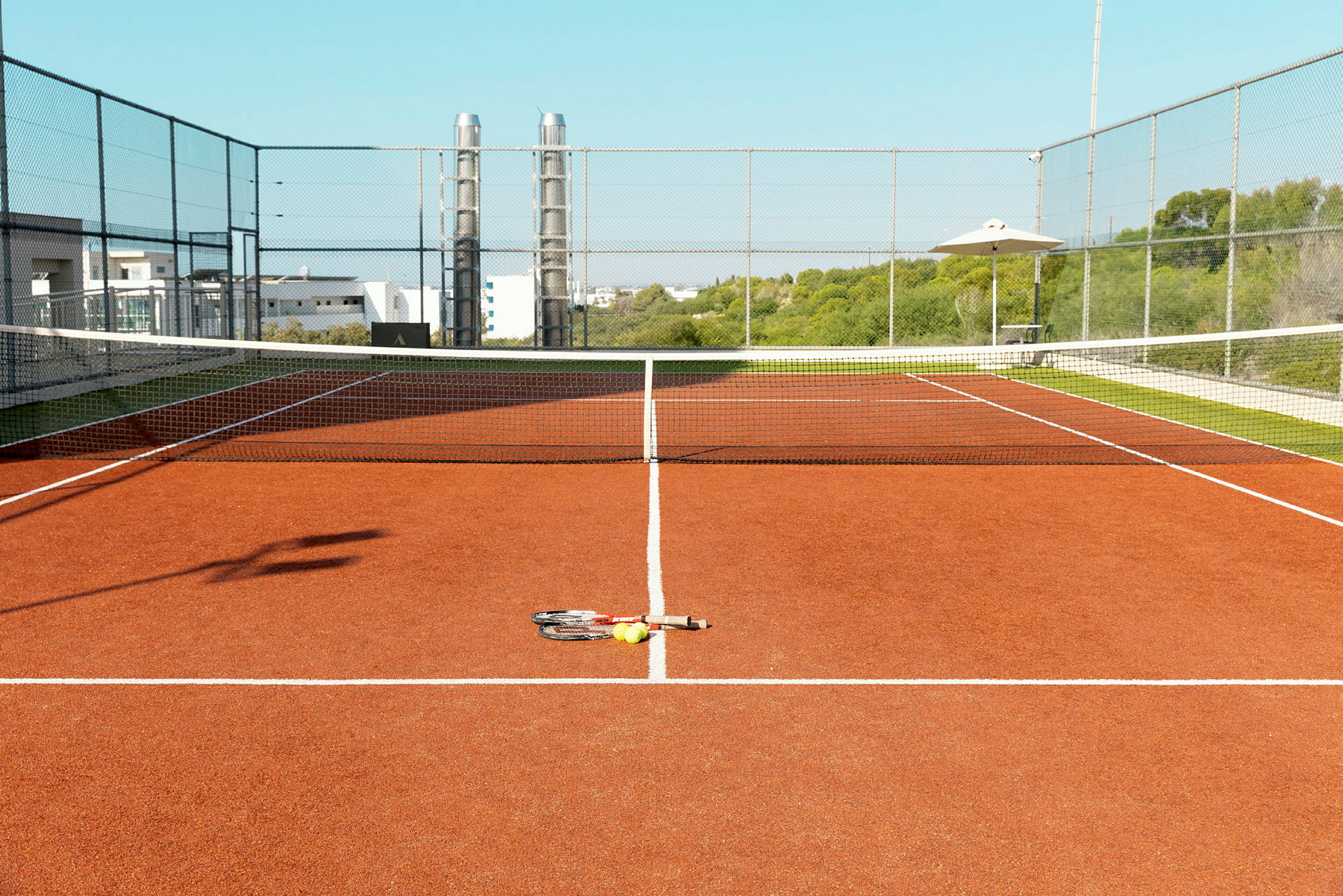 Billede af en tennisbane med ketcher og bolde på jorden. (AI-genereret tekst)
