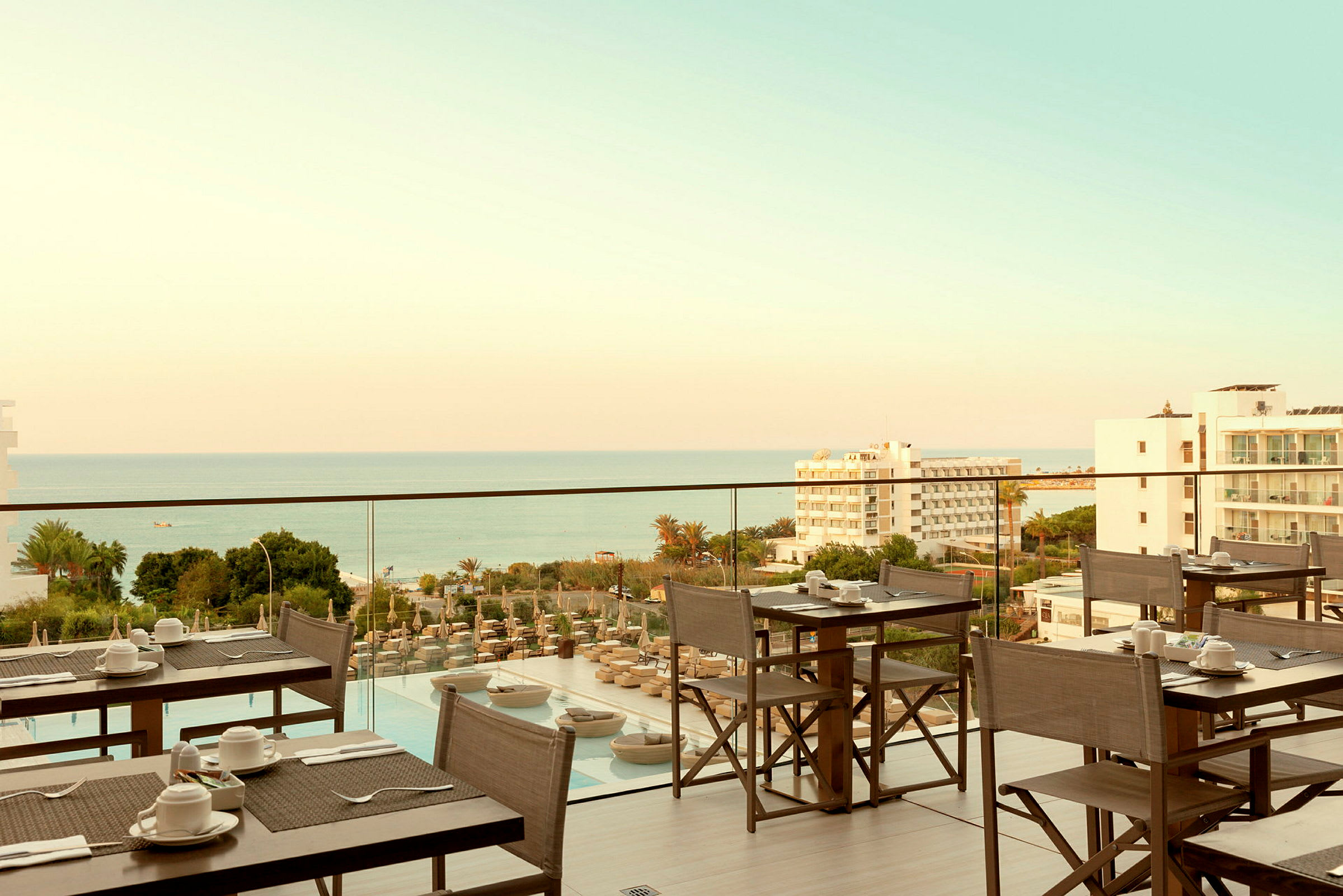 Restaurantterrasse med udsigt over havet og omkringliggende bygninger. (AI-genereret tekst)
