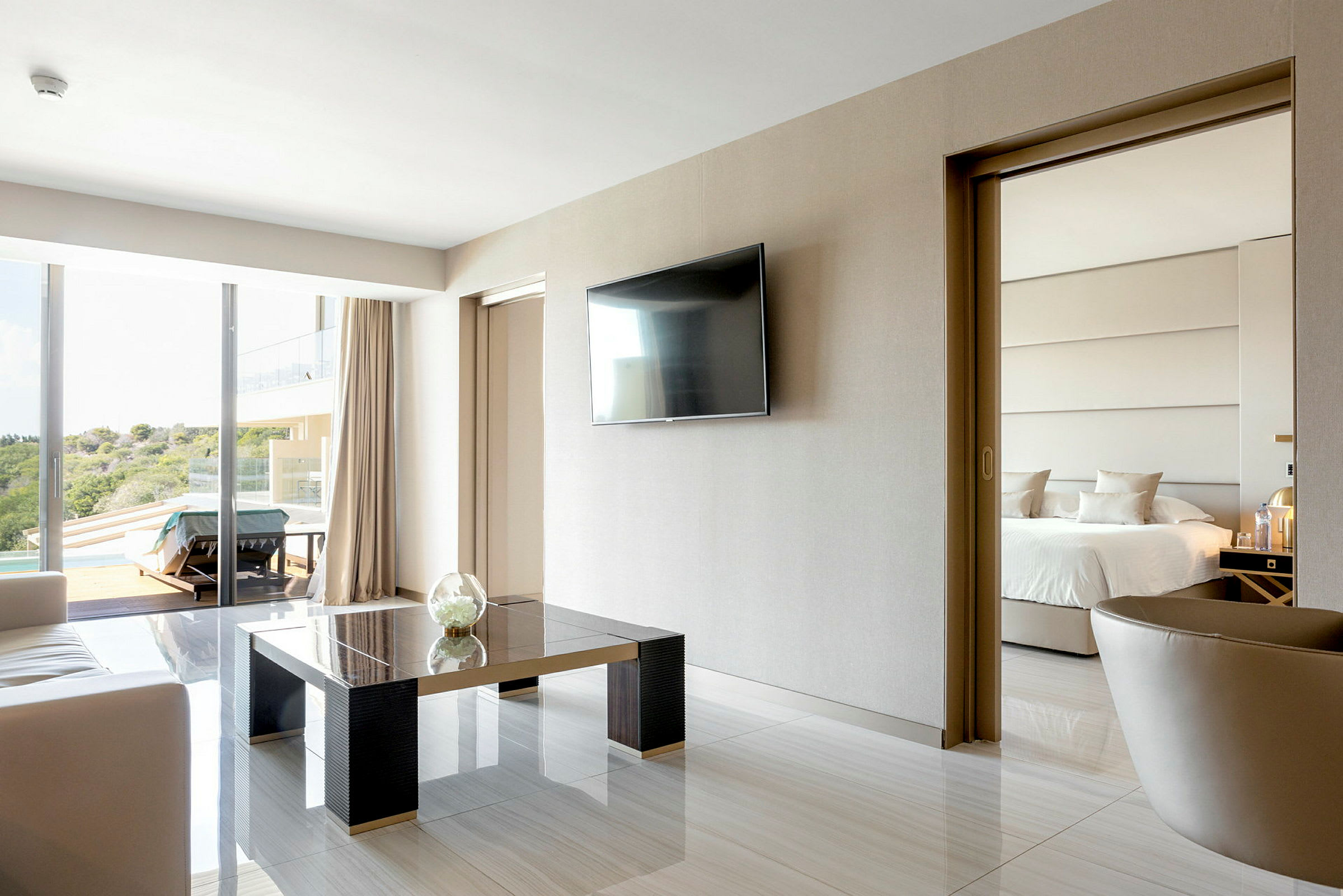 Moderne hotelværelse med siddeområde, TV på væggen og skydedør til soveværelset med en dobbeltseng. (AI-genereret tekst)