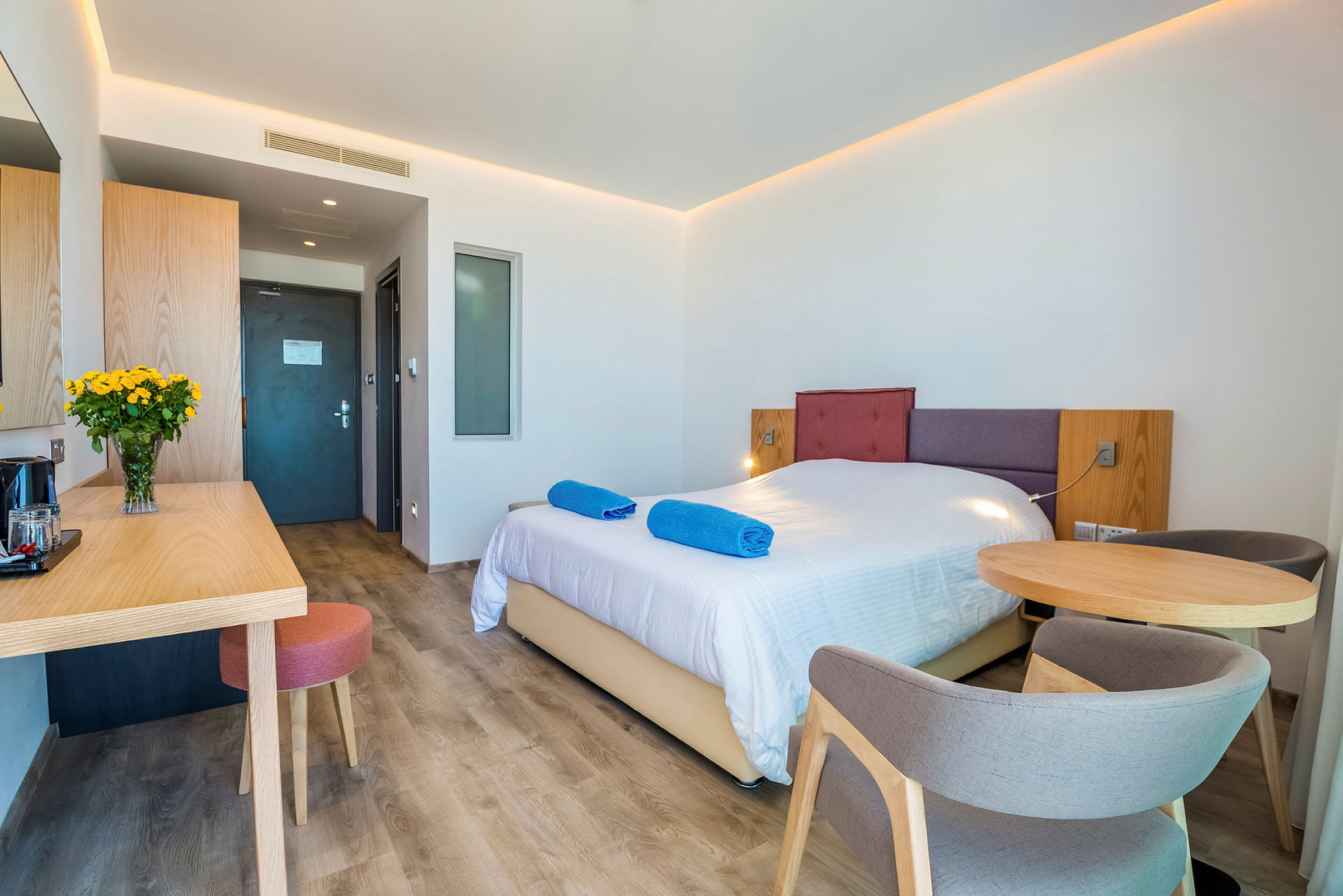 Hotelværelse med en dobbeltseng, et bord med stole og en skrivebordsplads. (AI-genereret tekst)