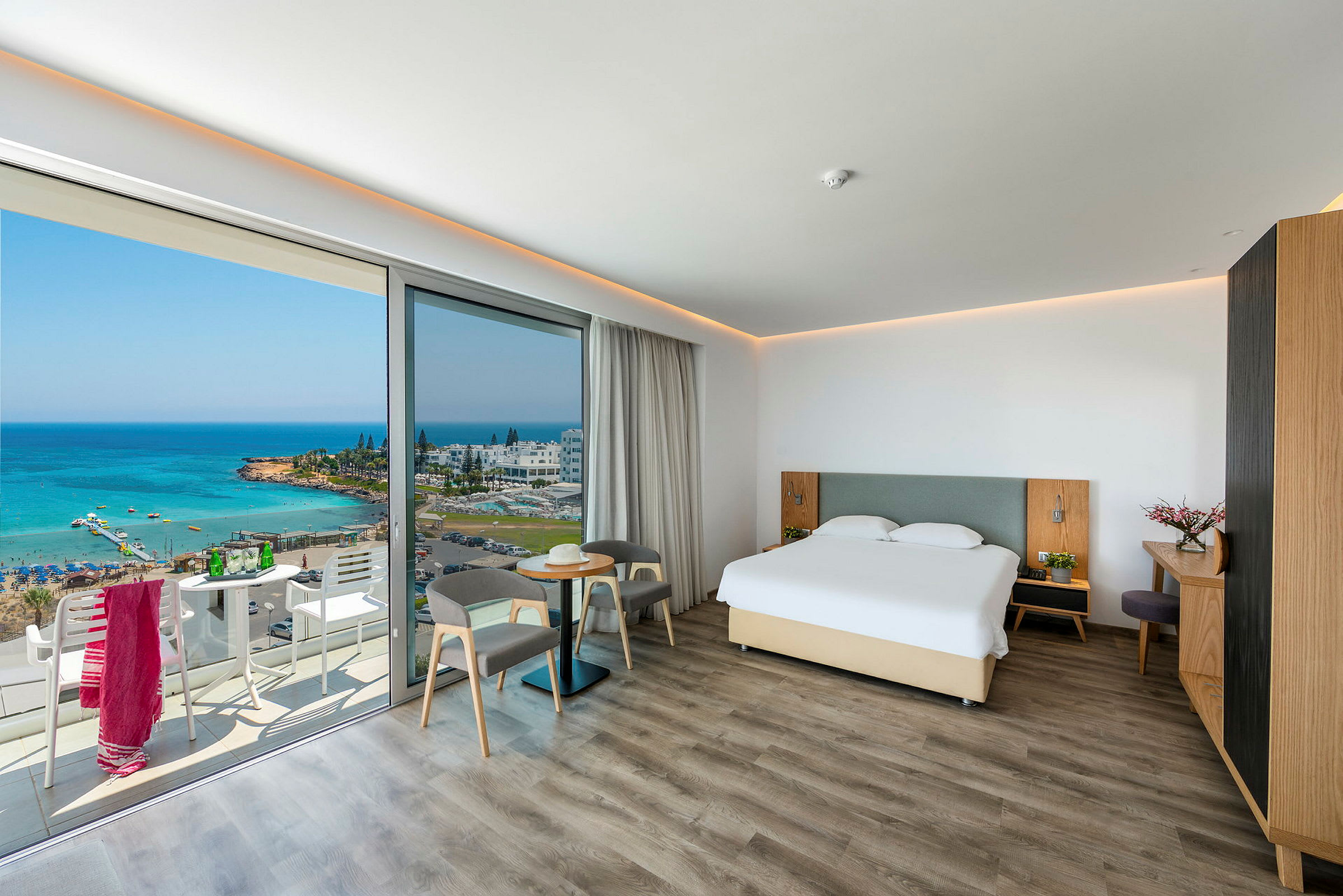Et hotelværelse med en dobbeltseng og en balkon med udsigt over havet. (AI-genereret tekst)