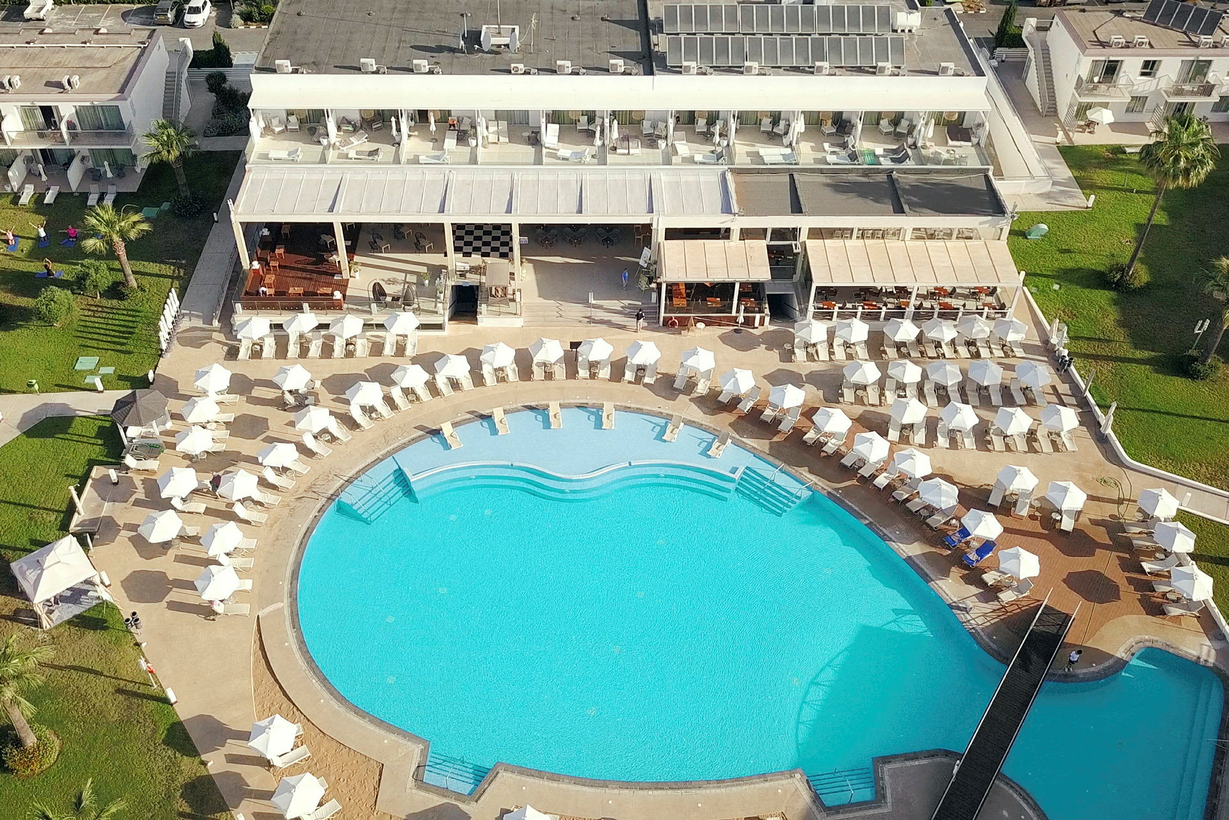 Luftfoto af hotelområde med stor pool og solsenge. (AI-genereret tekst)