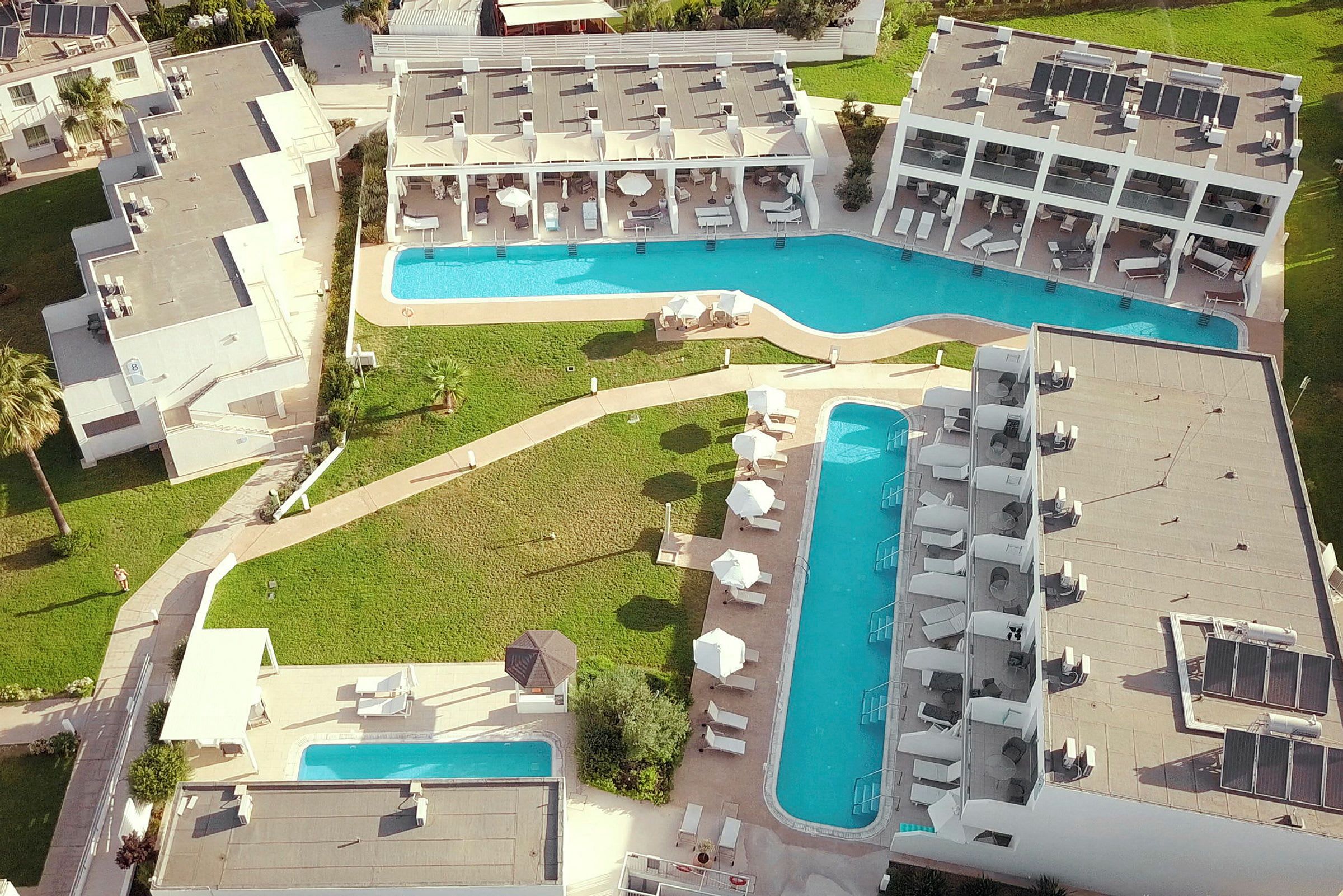 Luftfoto af hotel med poolområder og grønne områder. (AI-genereret tekst)