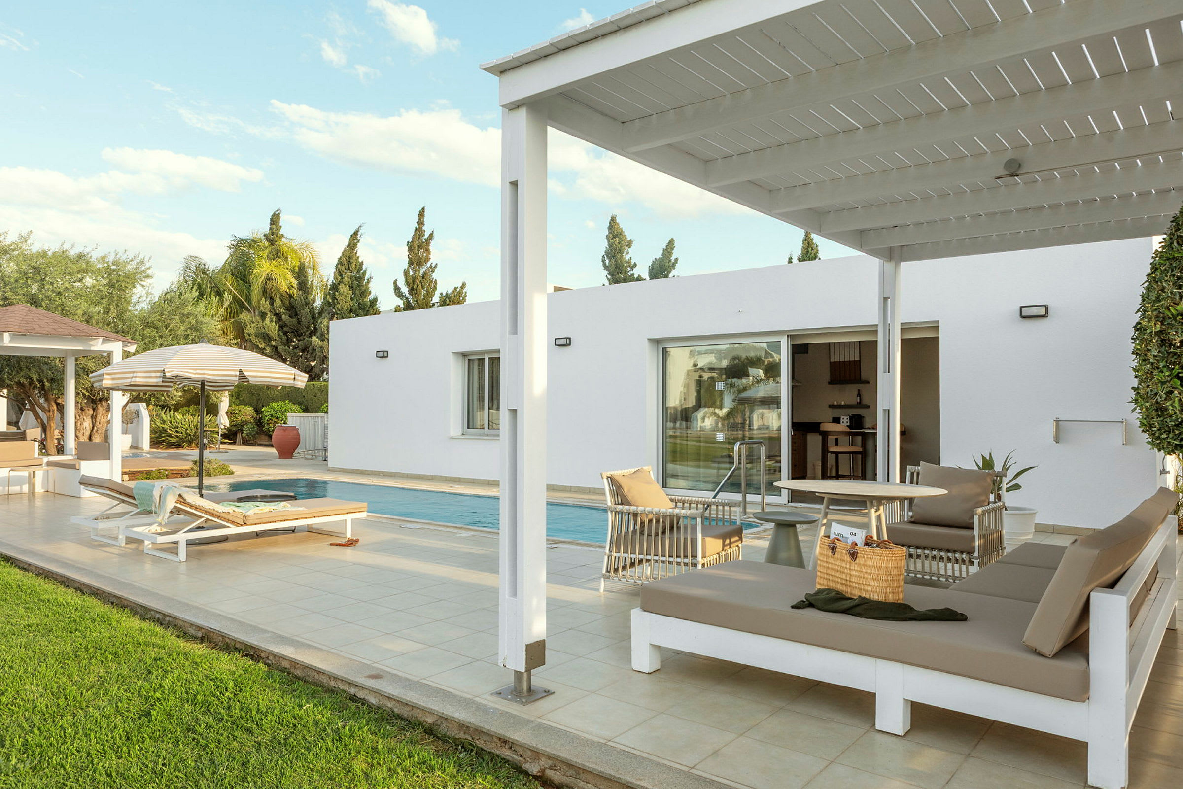 Udendørs område med en pool, liggestole og en pergola ved siden af en moderne bygning. (AI-genereret tekst)