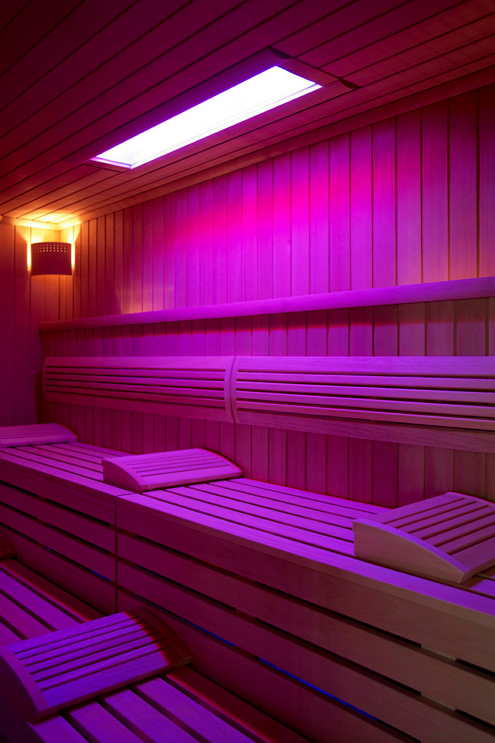 Interiør af en sauna med træbænke og farvet belysning. (AI-genereret tekst)