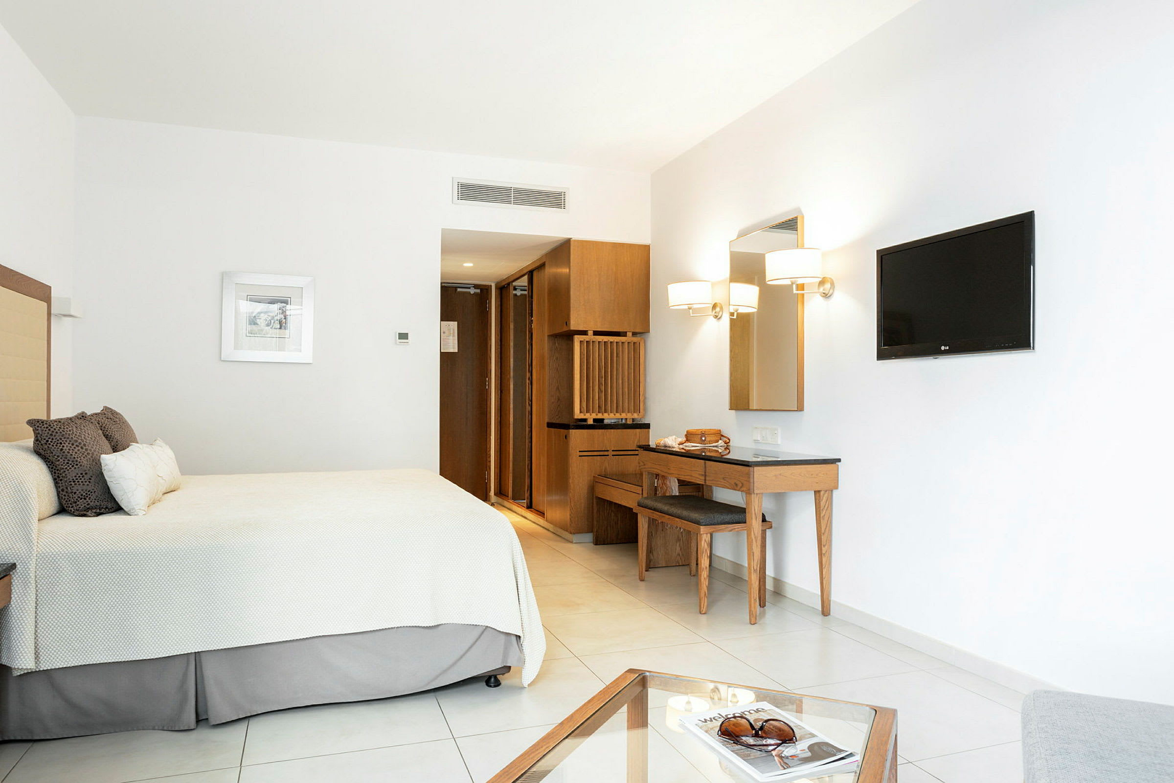 Et minimalistisk hotelværelse med seng, vægmonteret TV og skrivebord. (AI-genereret tekst)