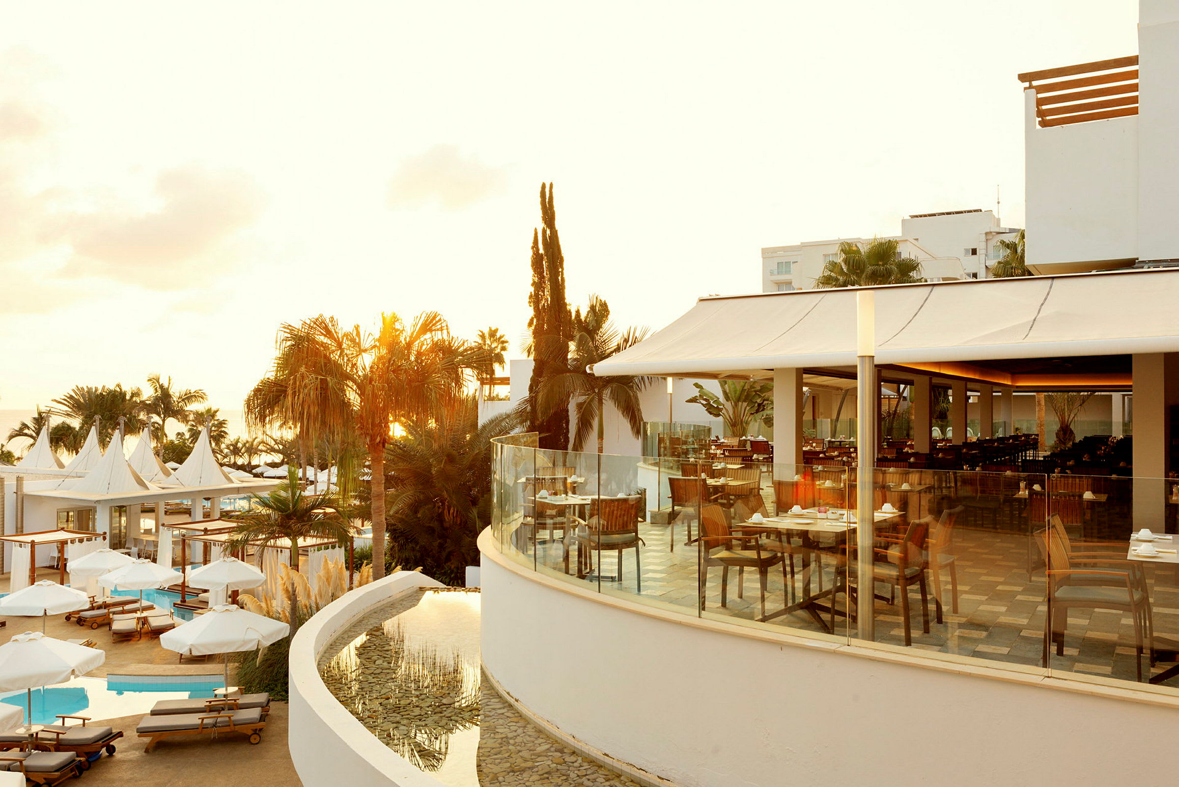 Udendørsområde ved hotel med udsigt over pool- og restaurantområde. (AI-genereret tekst)