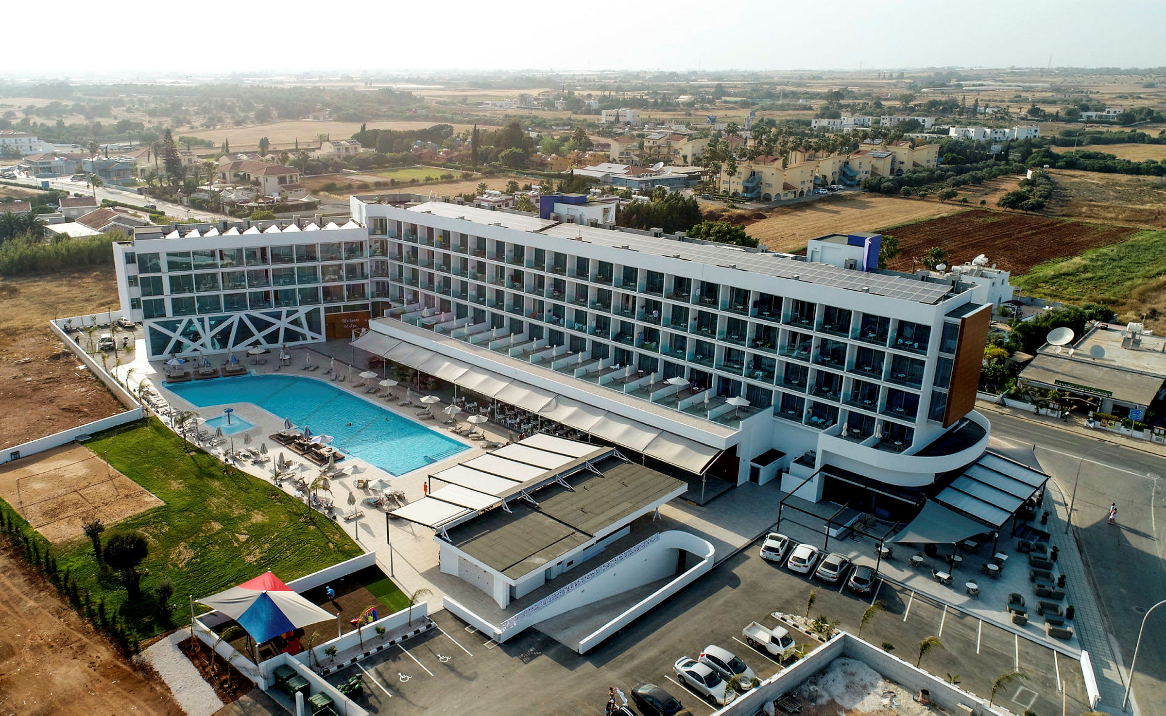 Hotelbygning med pool og omkringliggende landskab. (AI-genereret tekst)