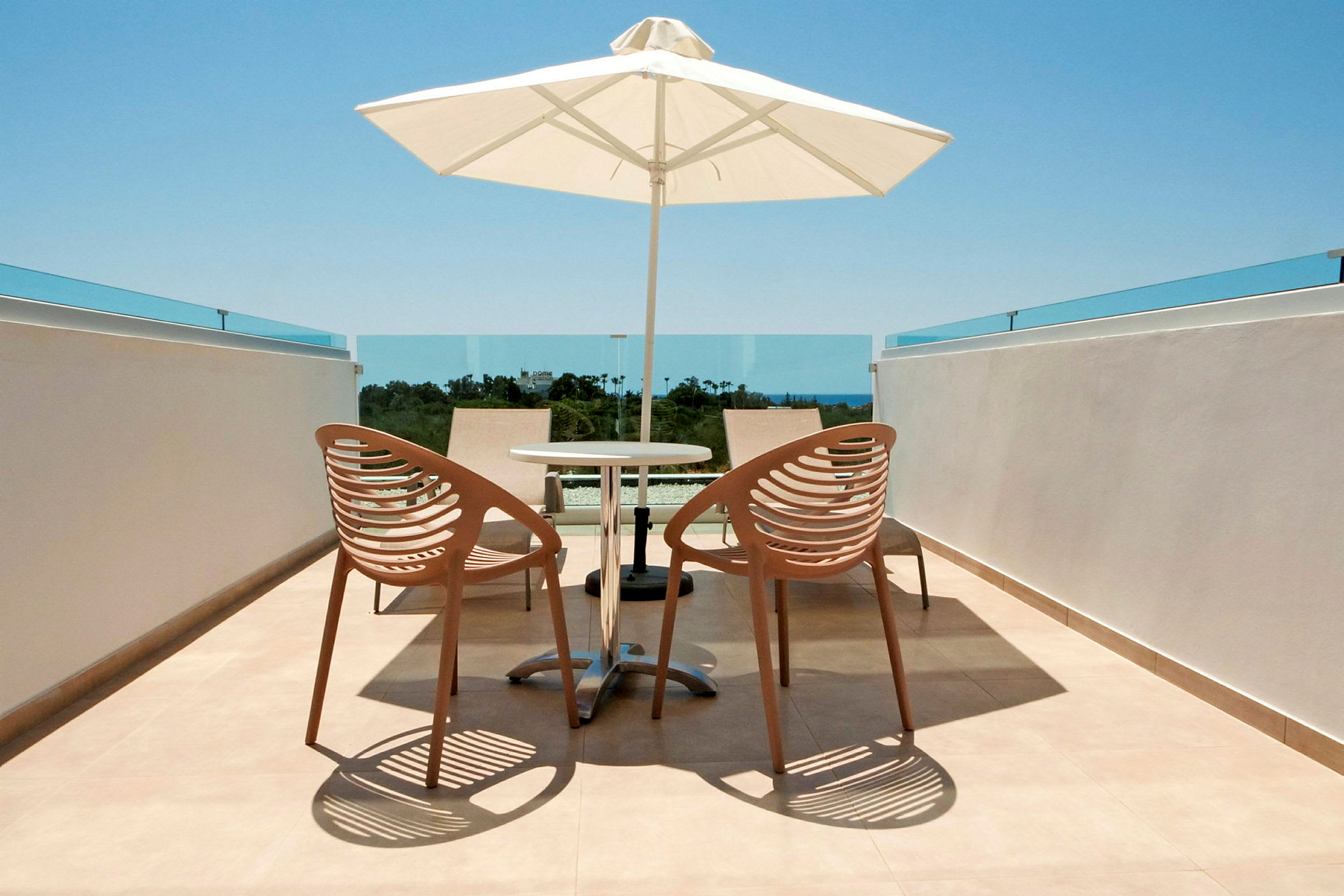Billede af en terrasse med to stole, et bord og en parasol. (AI-genereret tekst)