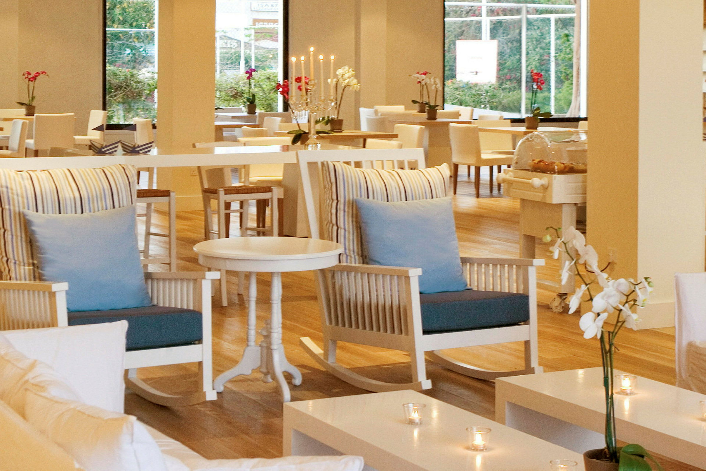 Interiør af en restaurant med lyse møbler, blomster og dekorationer. (AI-genereret tekst)