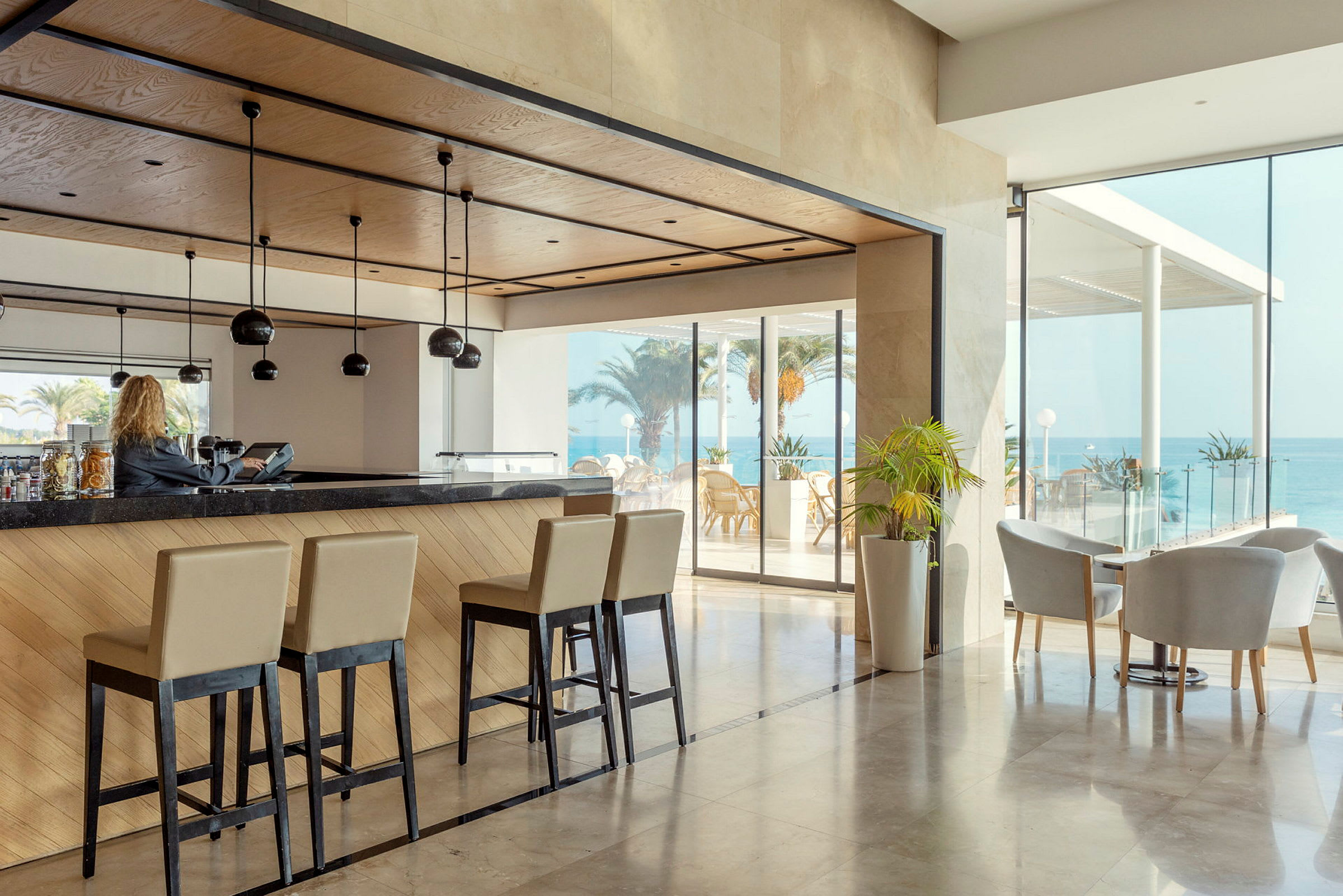 Hotelbar med høje stole og udsigt til havet. (AI-genereret tekst)