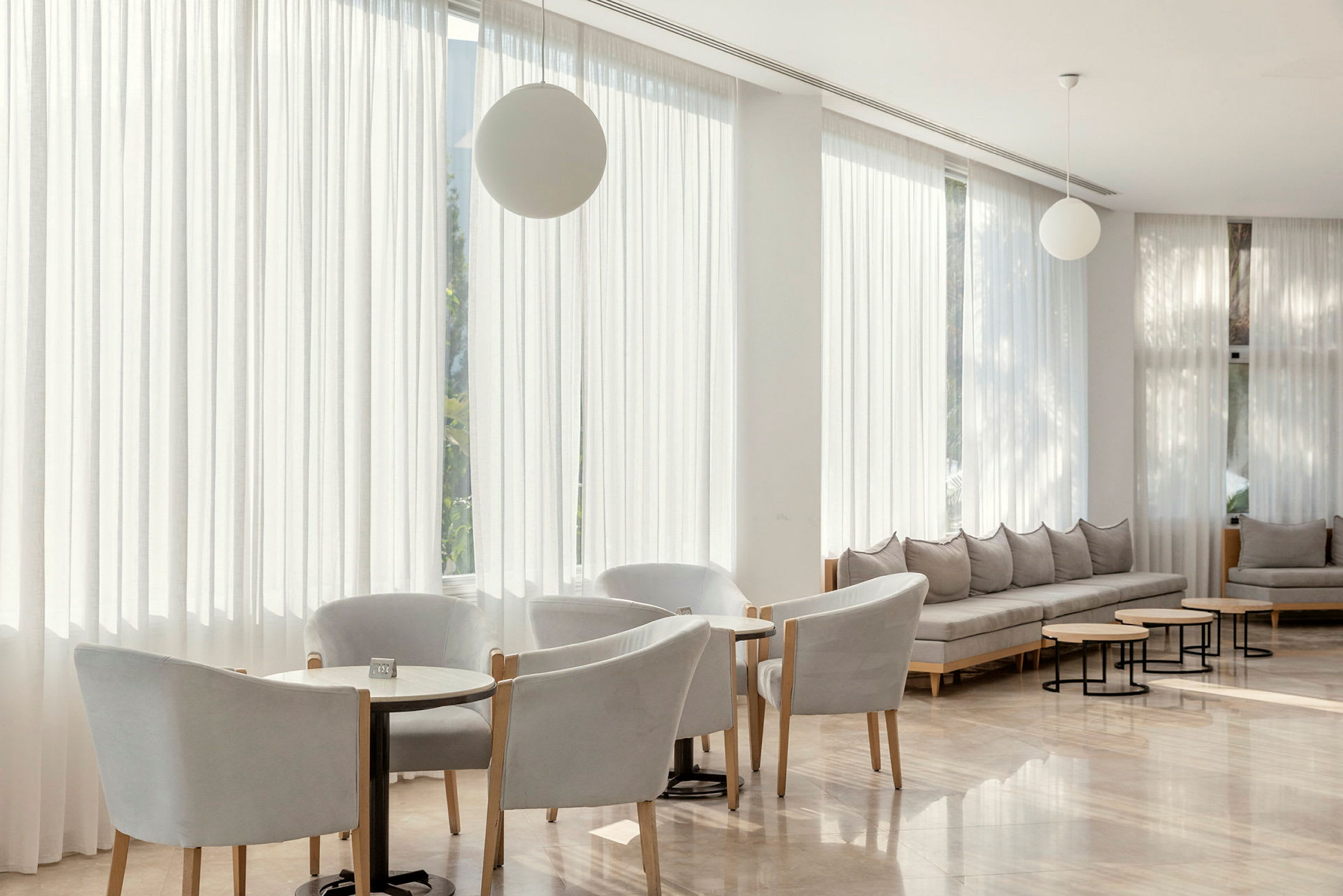En moderne lounge med stole, små borde og sofaer i lyse farver. (AI-genereret tekst)