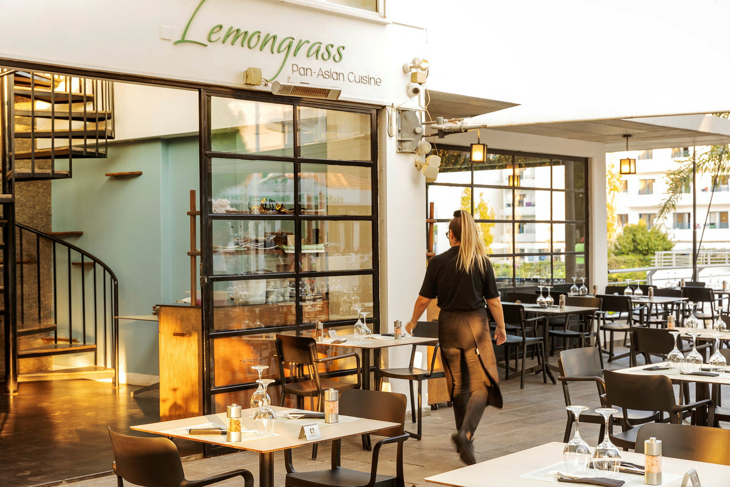 Restaurant med navnet Lemongrass og en tjener, der går mellem bordene. (AI-genereret tekst)