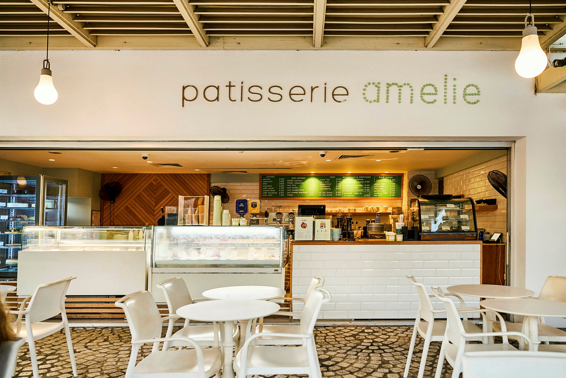 Et café med skiltet "patisserie amelie" og en indbydende serveringsdisk med borde og stole foran. (AI-genereret tekst)