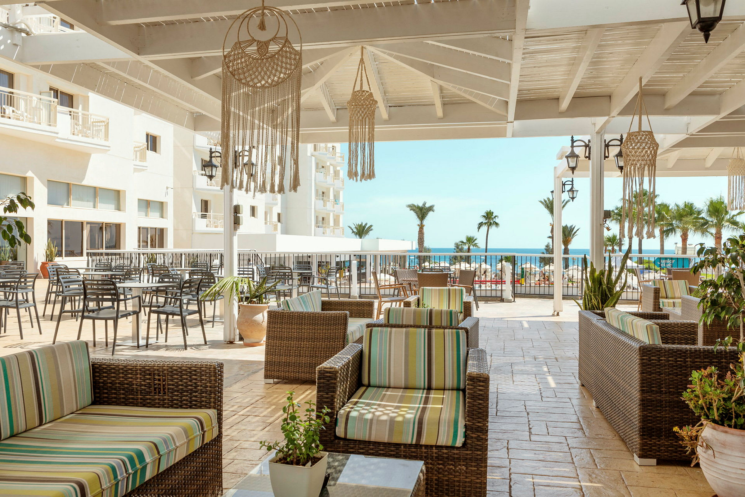 Terrasse med siddepladser og udsigt til havet. (AI-genereret tekst)