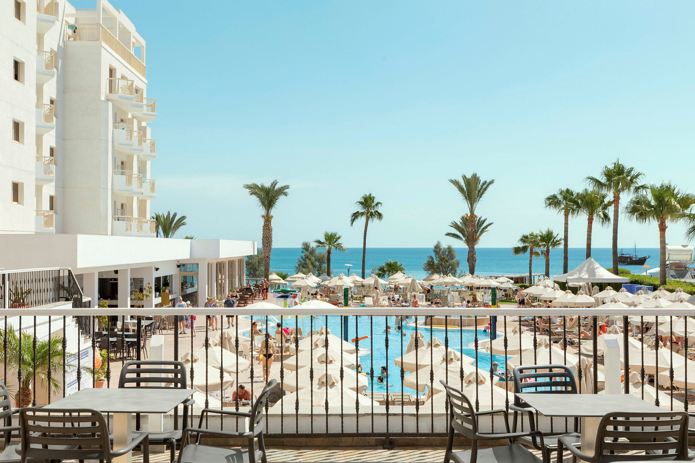 Hotelområde med pool, parasoller og havudsigt. (AI-genereret tekst)