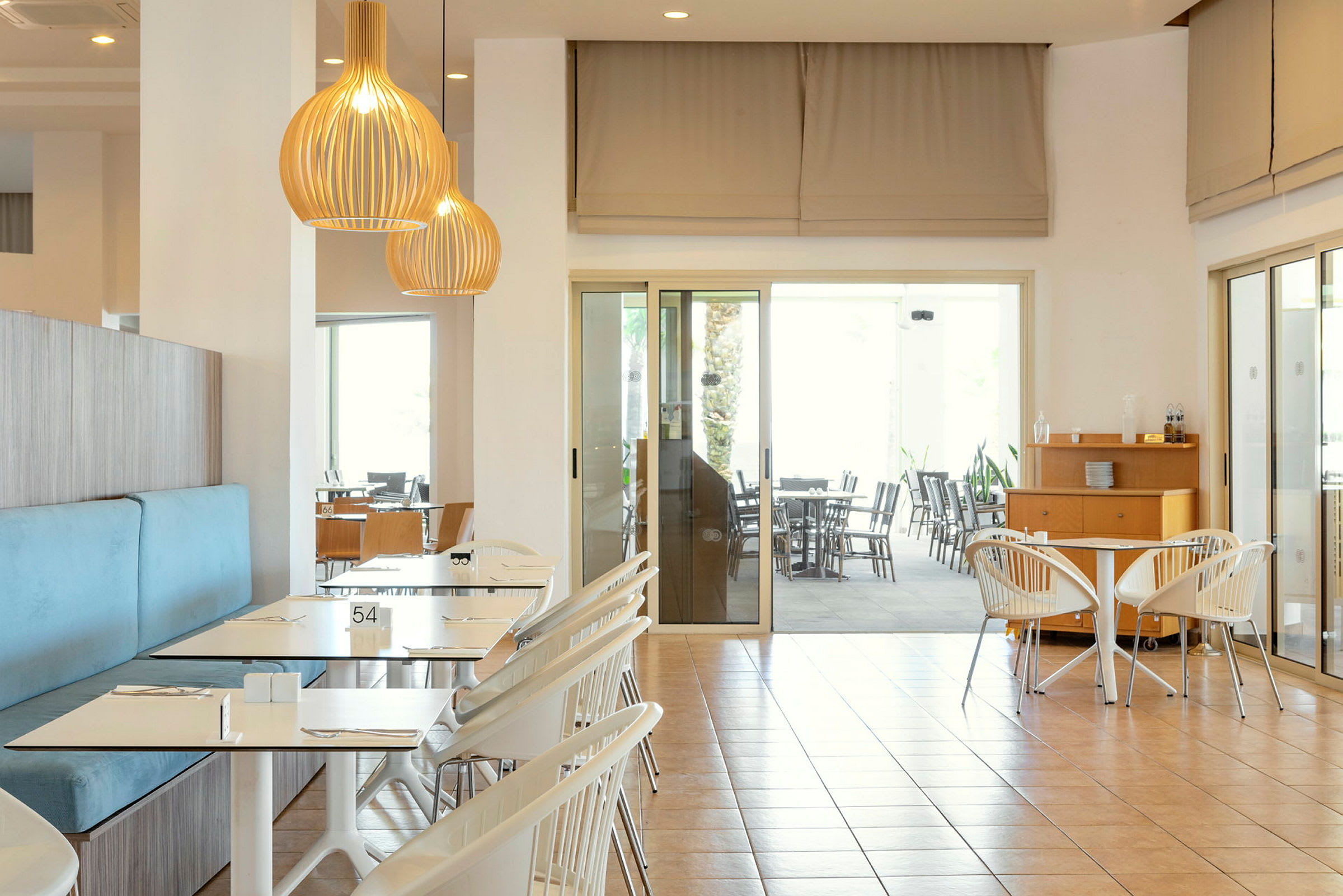 Interiør af en lys restaurant med borde og stole samt loftslamper. (AI-genereret tekst)