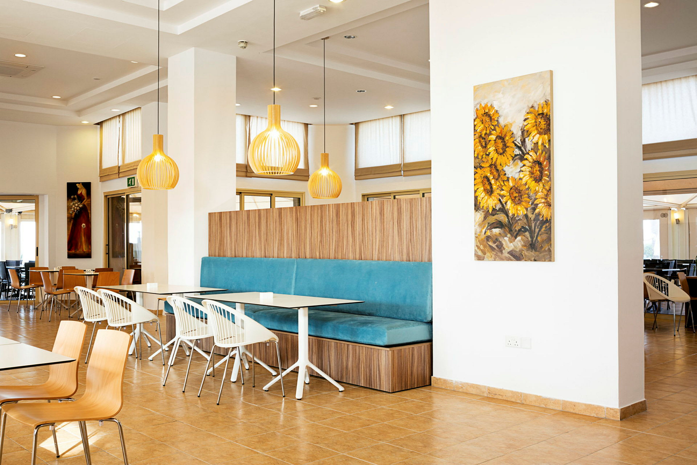 Interiør af en restaurant med moderne indretning og farverigt vægkunstværk med solsikkemotiv. (AI-genereret tekst)